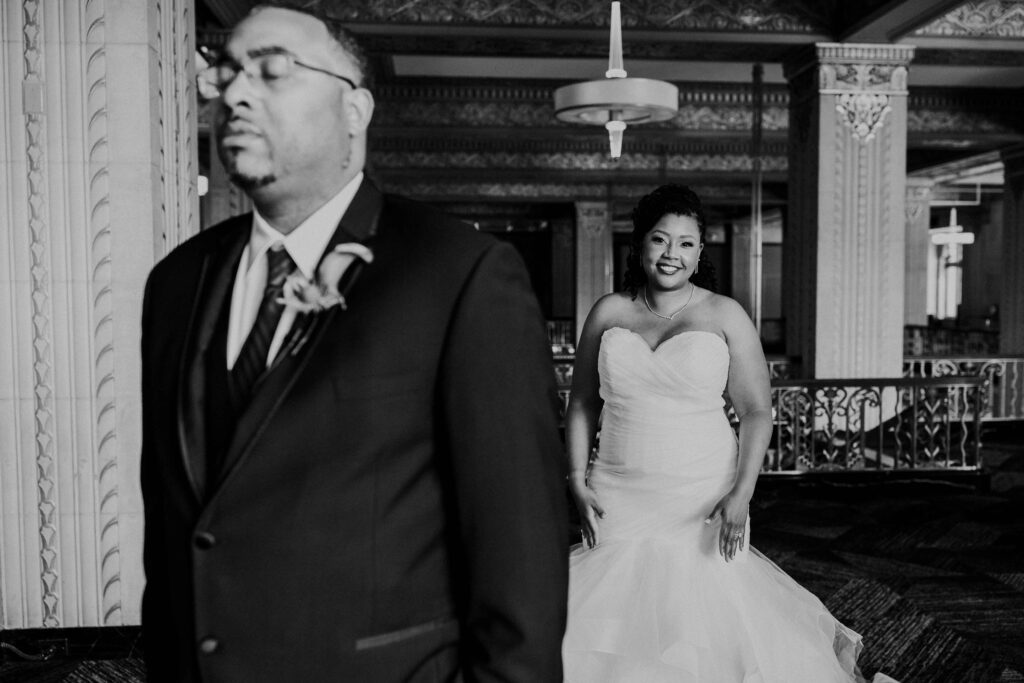 Bride smiling behind the groom before their first look.