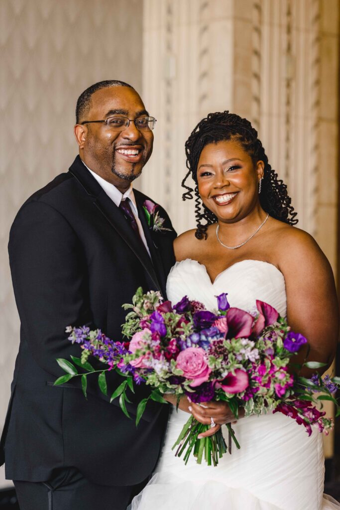 Bride and groom smiling while the bride holds her wedding bouquet at The Grand Hall at Power & Light.