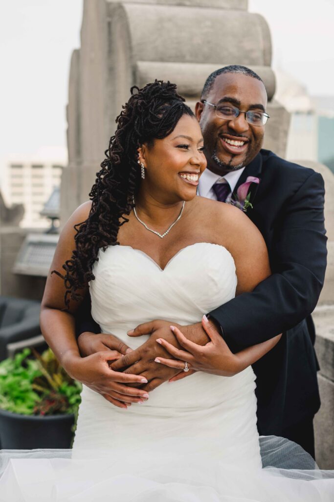 Groom with his arms wrapped around his bride.