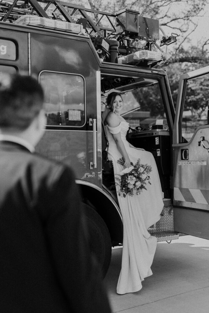 Groom looking at his wife sitting in a fire truck.