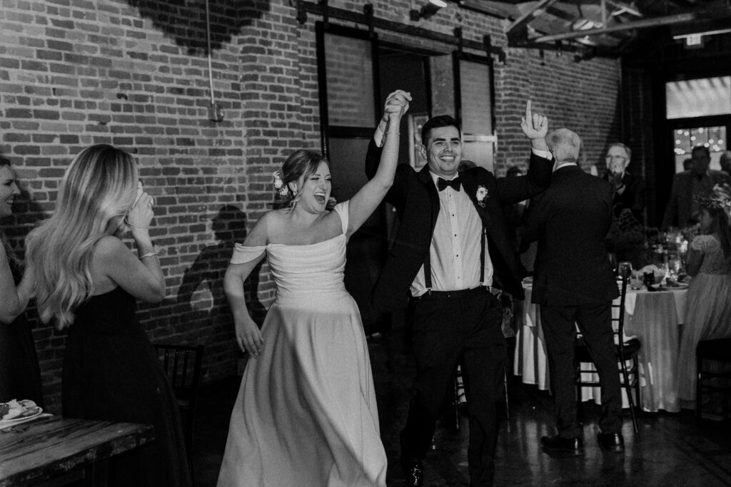 Bride and groom smiling while entering their wedding reception at The Guild KC.