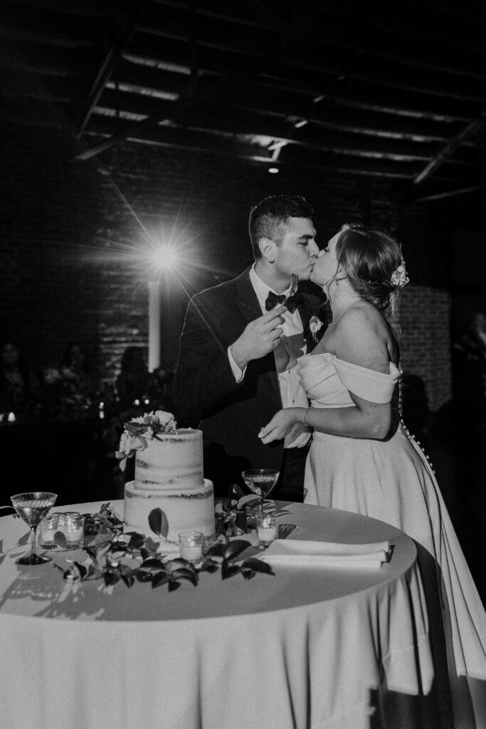 Bride and groom kissing after cutting cake.