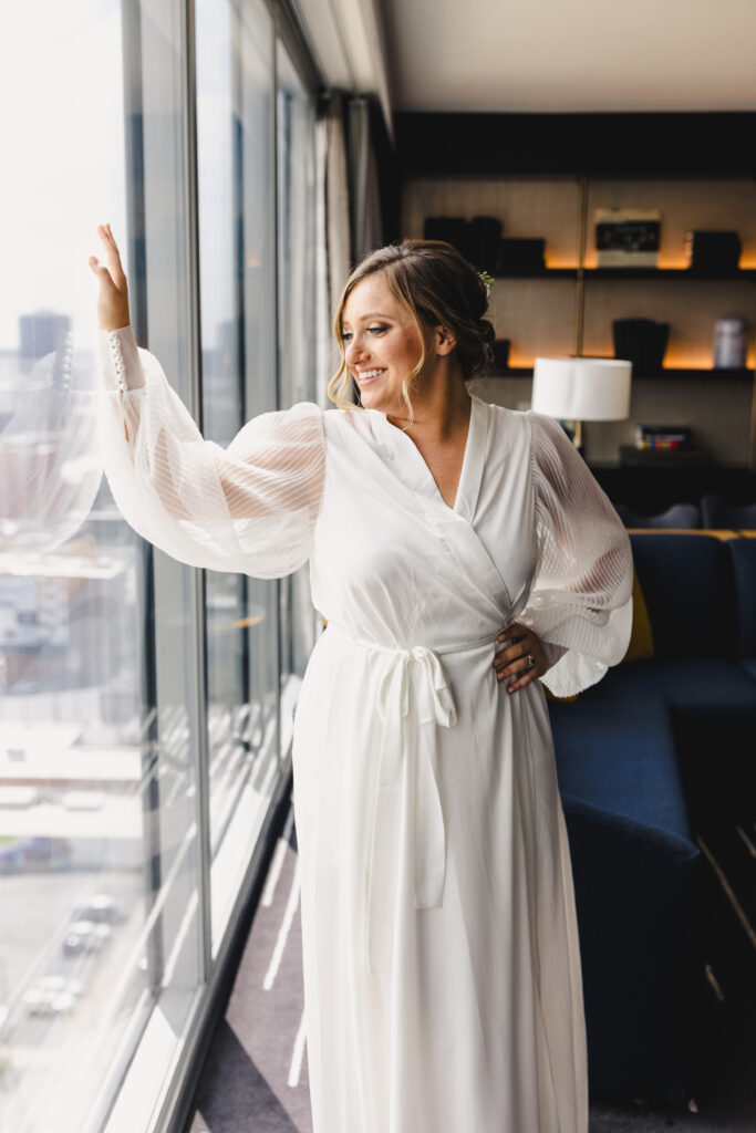 Bride in robe looking over downtown Kansas City.