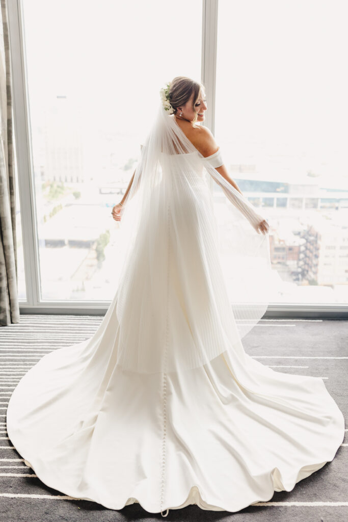 Bride smiling while looking down at her wedding dress.