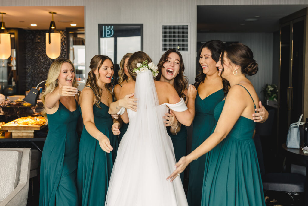 Bridesmaids hugging the bride with big smiles.
