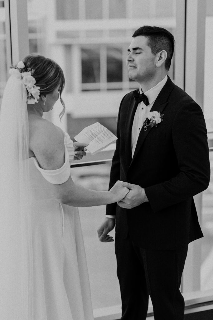 Groom holding back tears while the bride reads her personal vows.