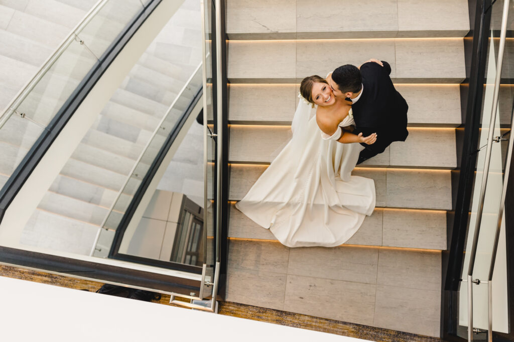 Bride and groom kissing in the stairwell of a hotel before heading to The Guild KC.