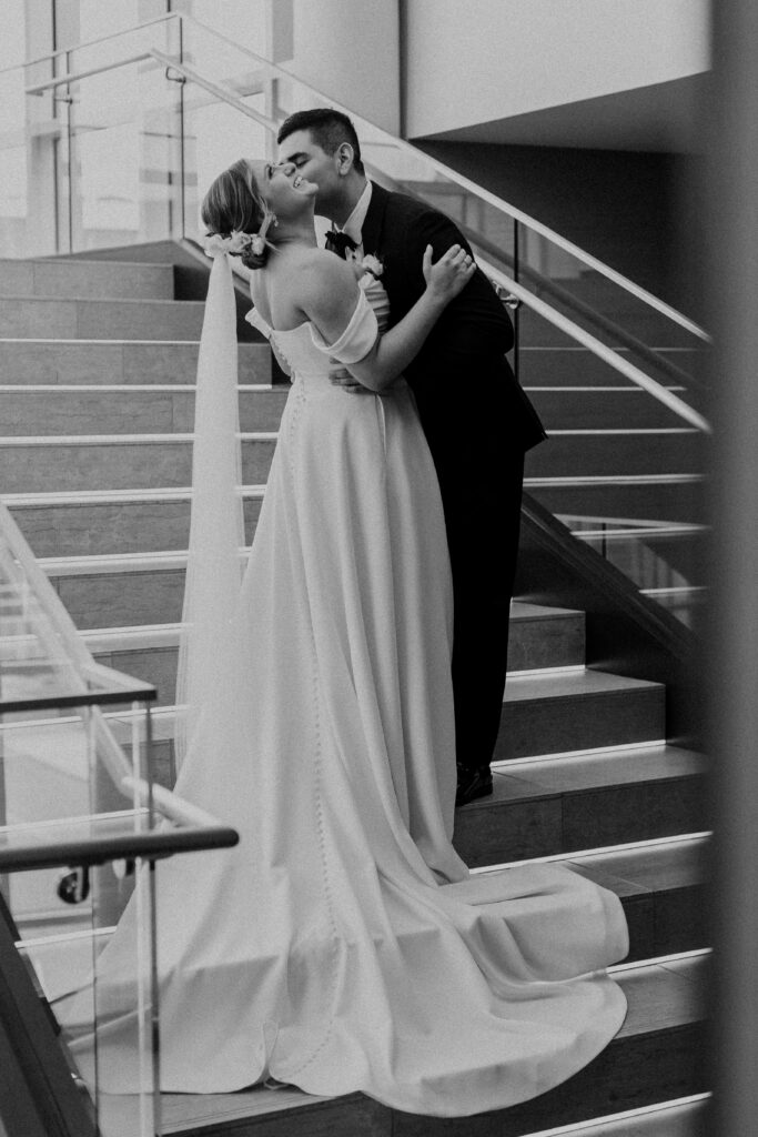 Groom kissing his bride in a stairwell.
