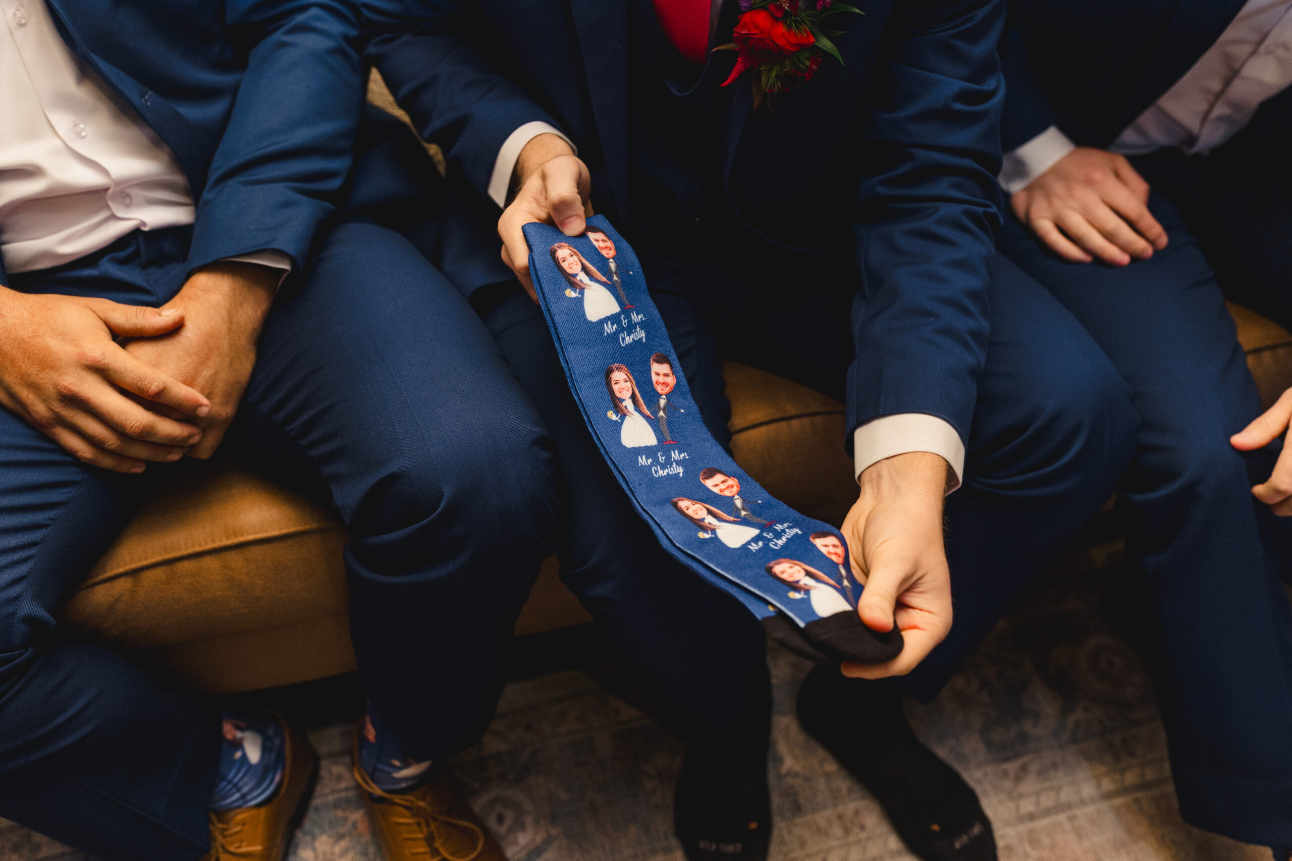 a groom holding up a pair of socks with his partner's face on them 