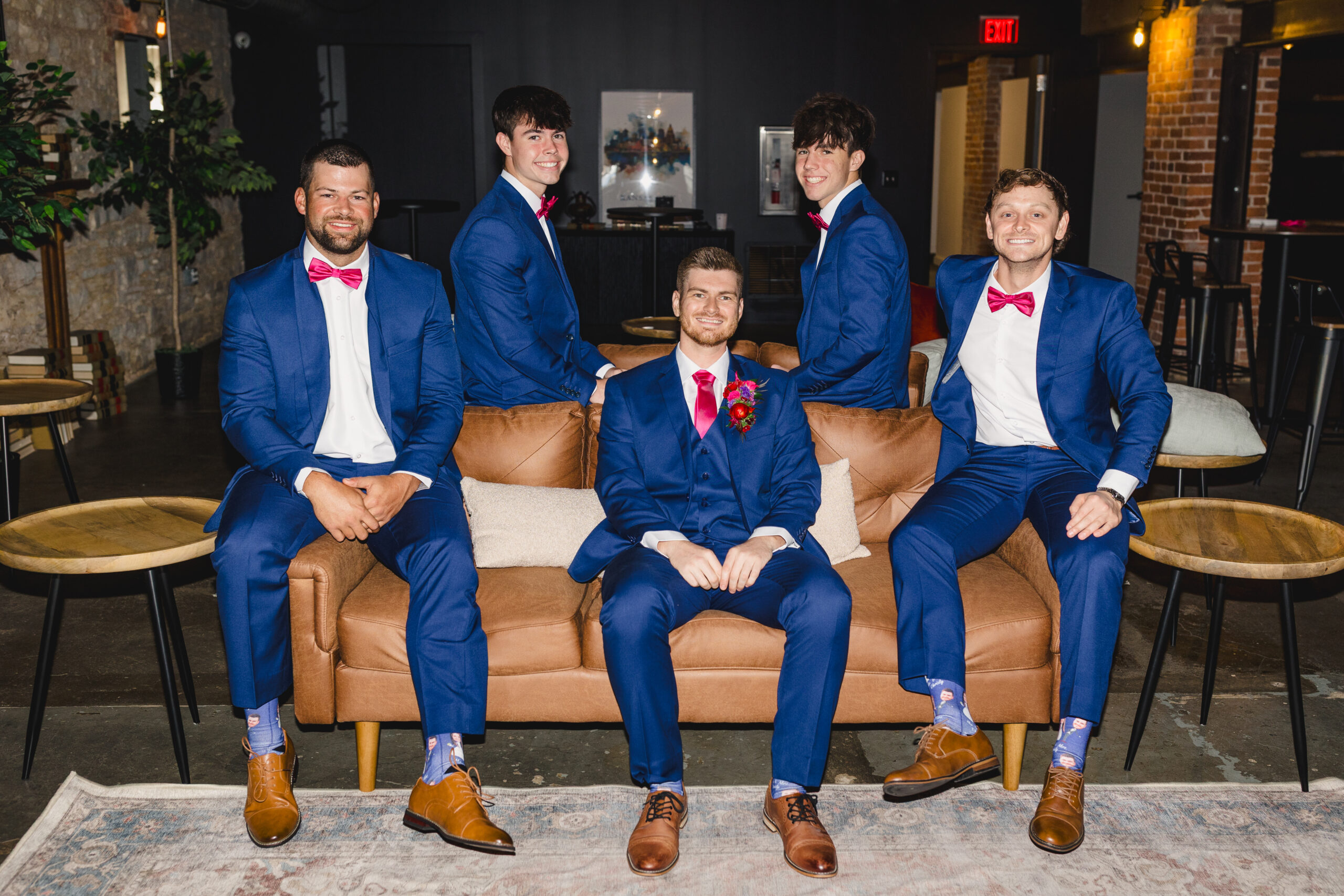a group of groomsmen with the groom sitting together on a leather couch 