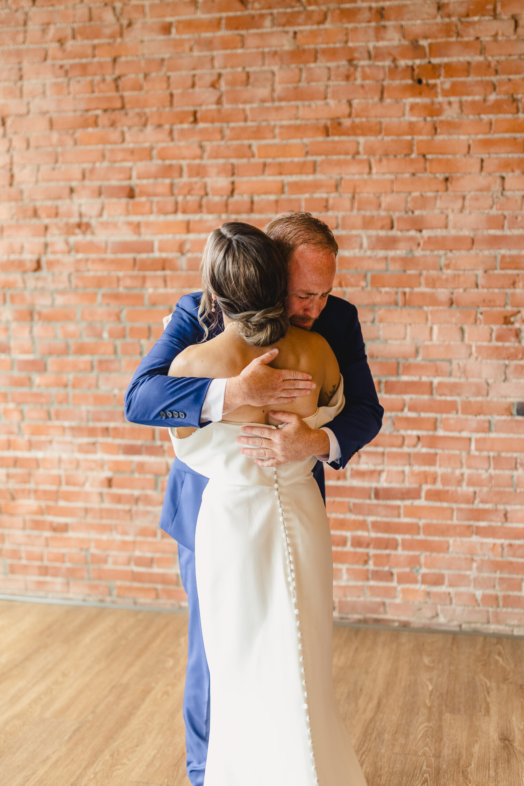 a father hugging his daughter after sharing a first look with her on the day of her wedding 