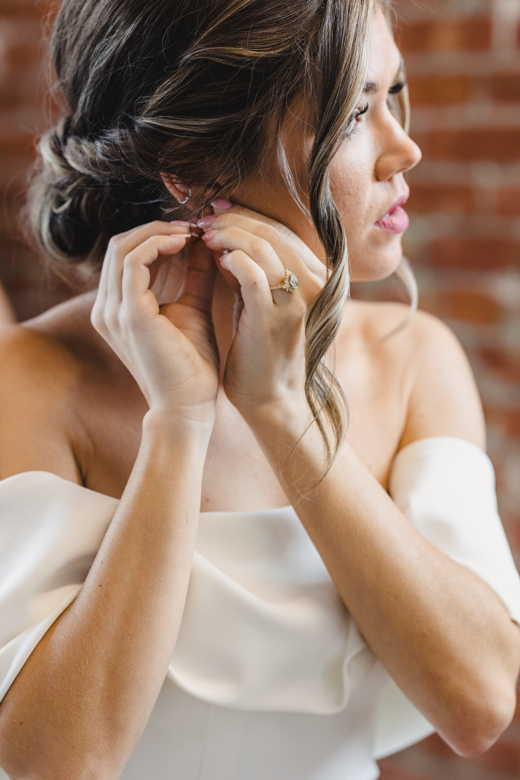 a bride putting an earring in her ear on the day of her wedding as she gets ready