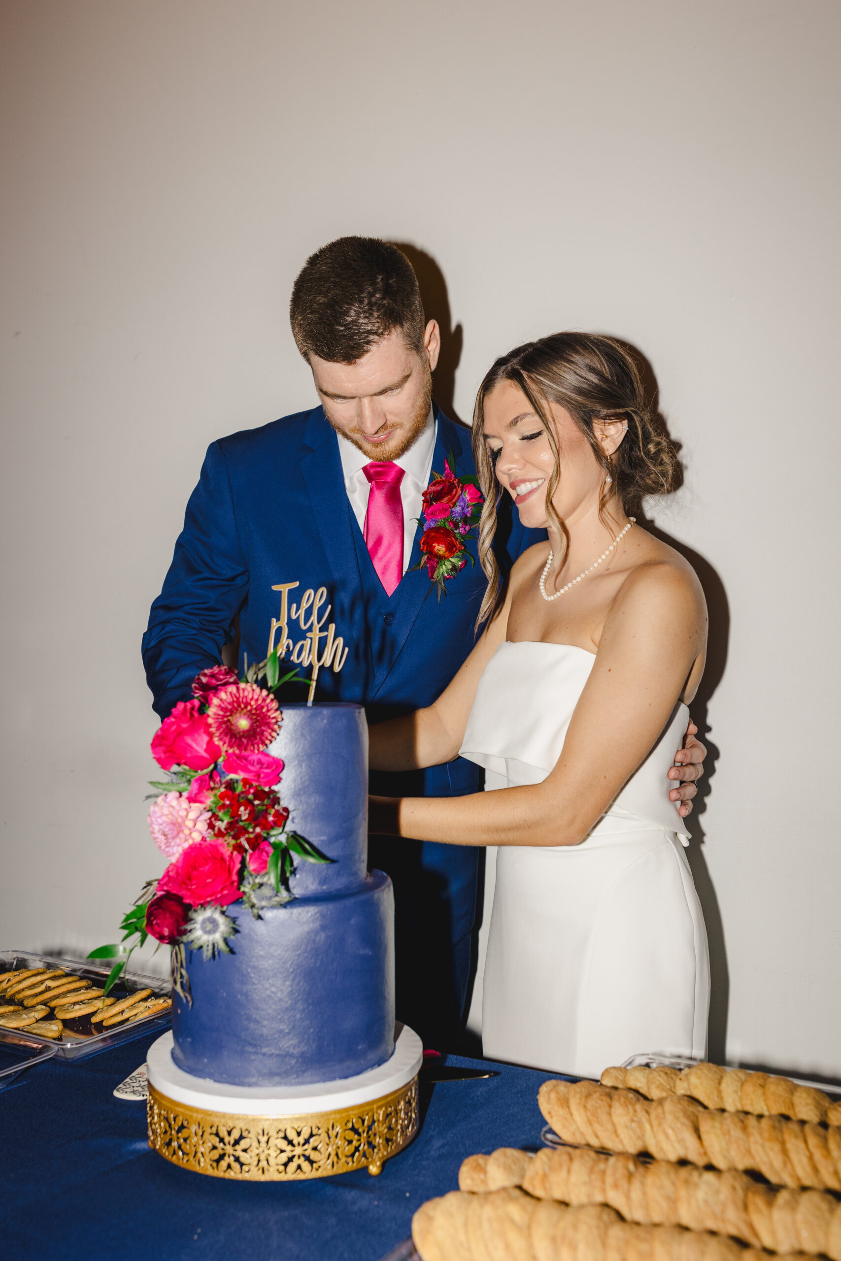 a bride and groom cutting together their blue wedding cake at their wedding reception 