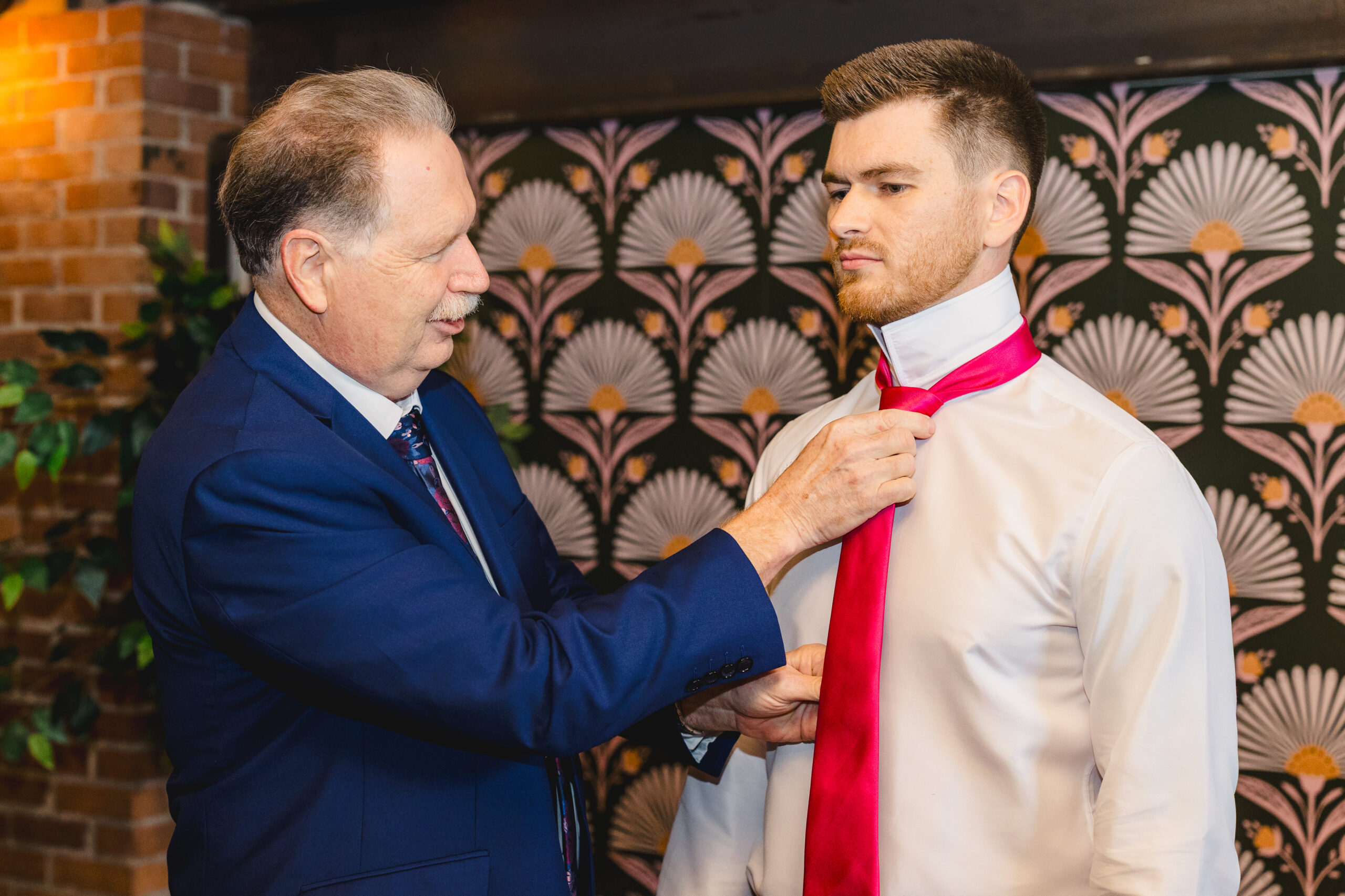 a father putting a tie on his son on the day of his wedding 