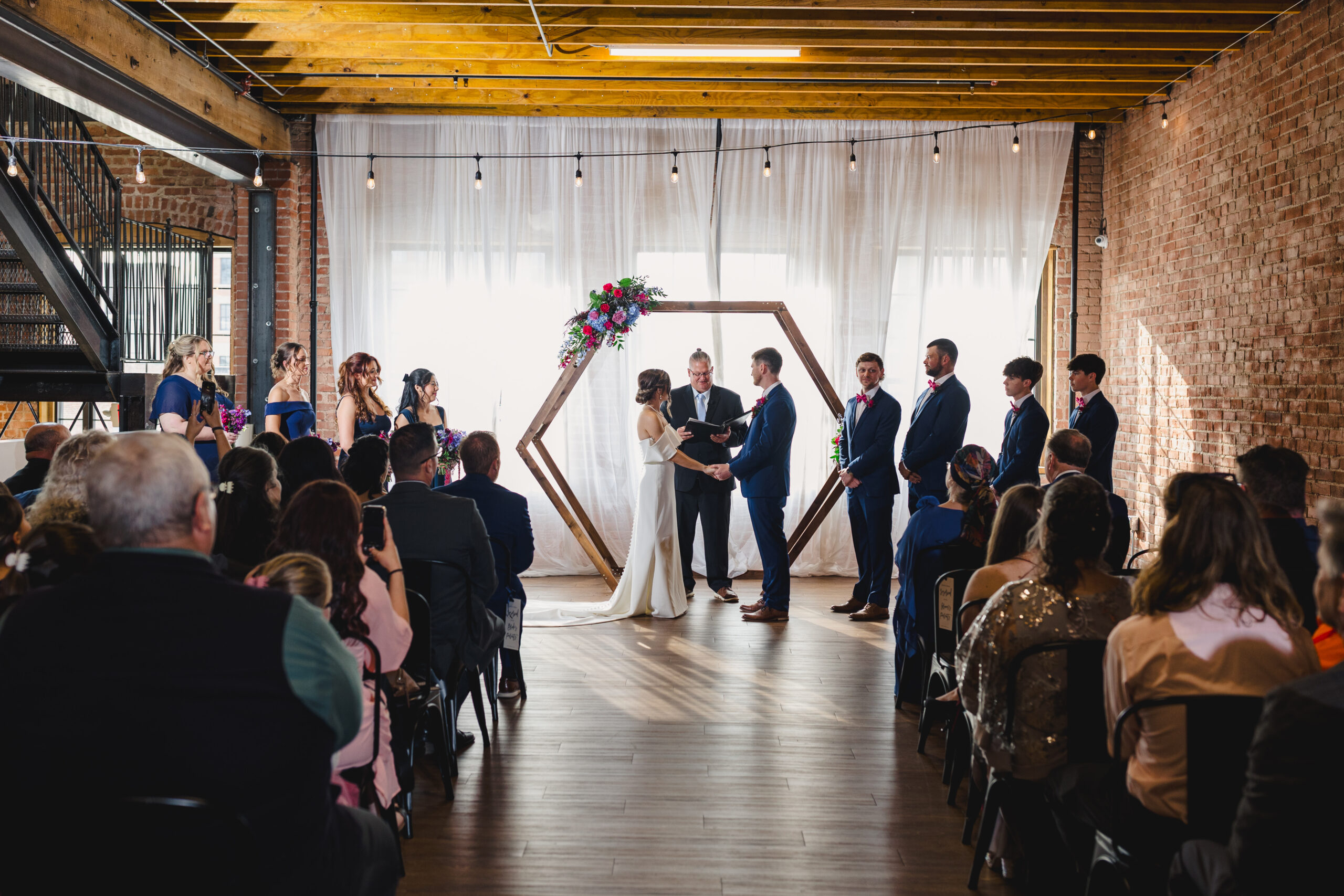 a couple at their wedding ceremony holding hands. Their wedding ceremony is taking place inside of union in kansas city 