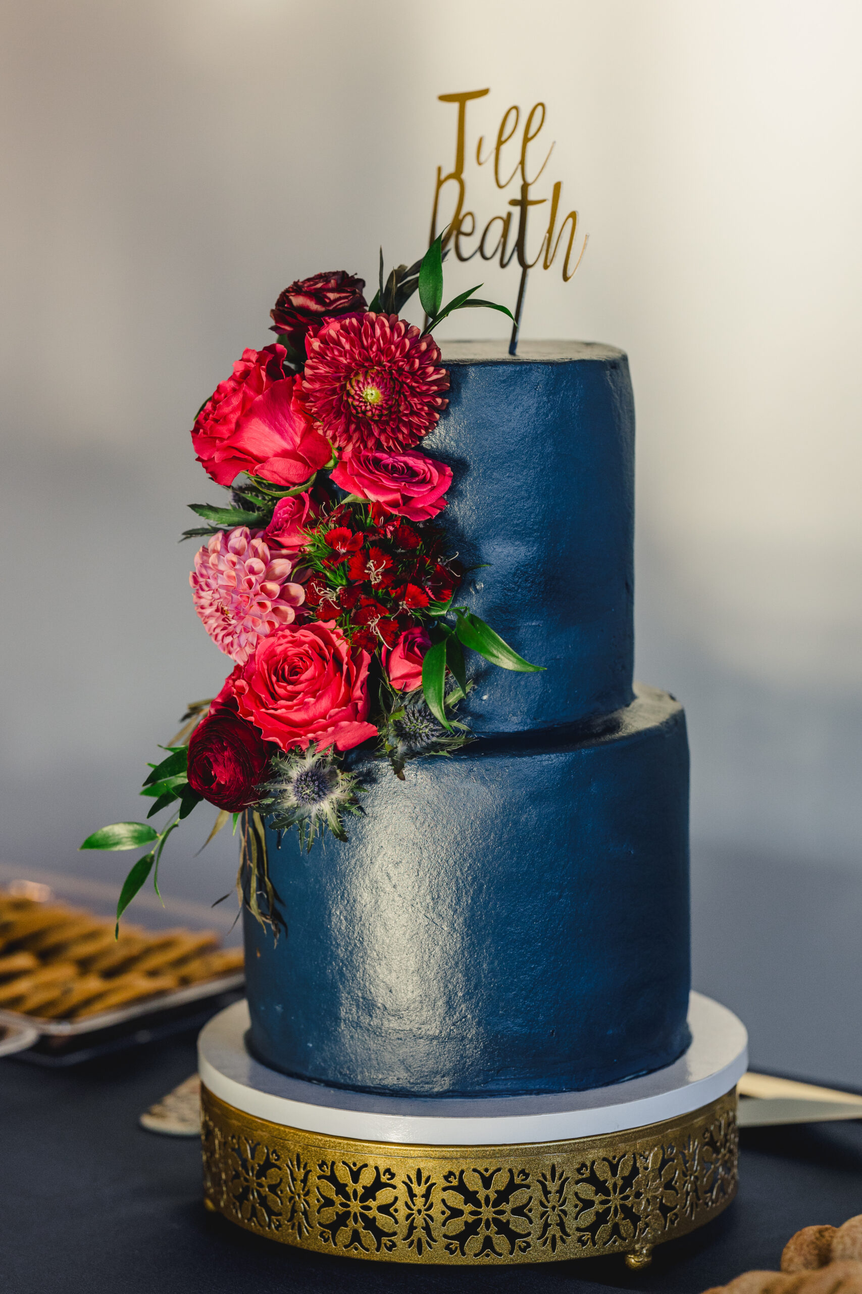 a blue cake with pink flowers on it and a wedding topper that says till death 