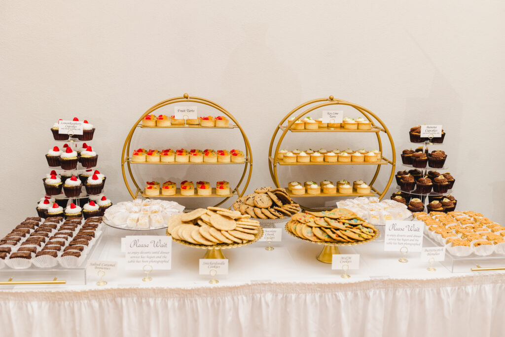 a table with various desserts at a wedding reception including cookies and cupcakes 