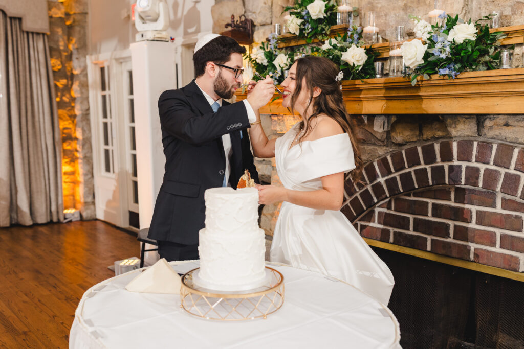 a couple enjoying their wedding cake together at their wedding reception inside of the elms hotel in kansas city