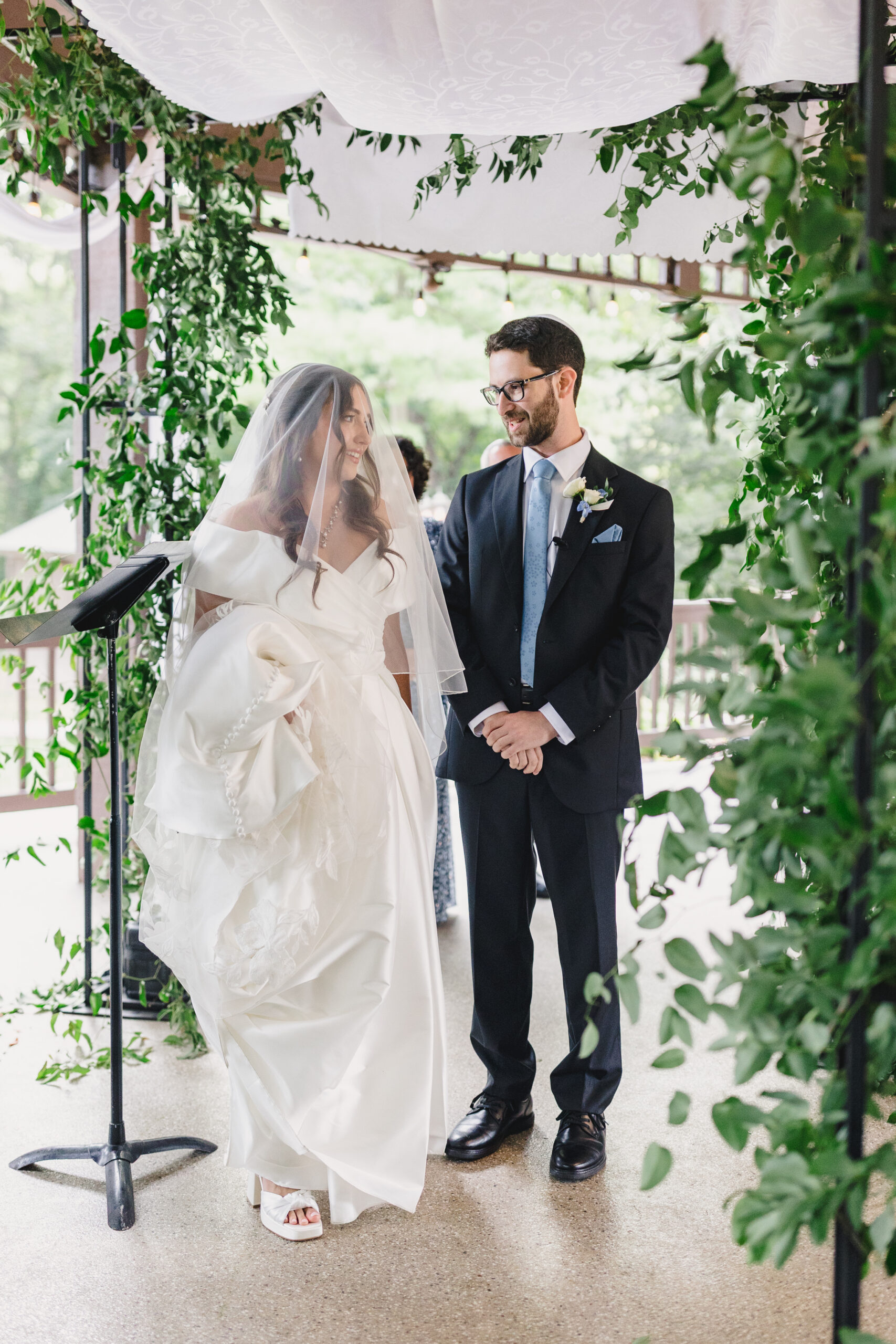 a couple in a gazebo at the elms hotel in kansas city getting ready for their wedding ceremony the bride is wearing a white wedding dress and veil and the groom is wearing a black tuxedo 