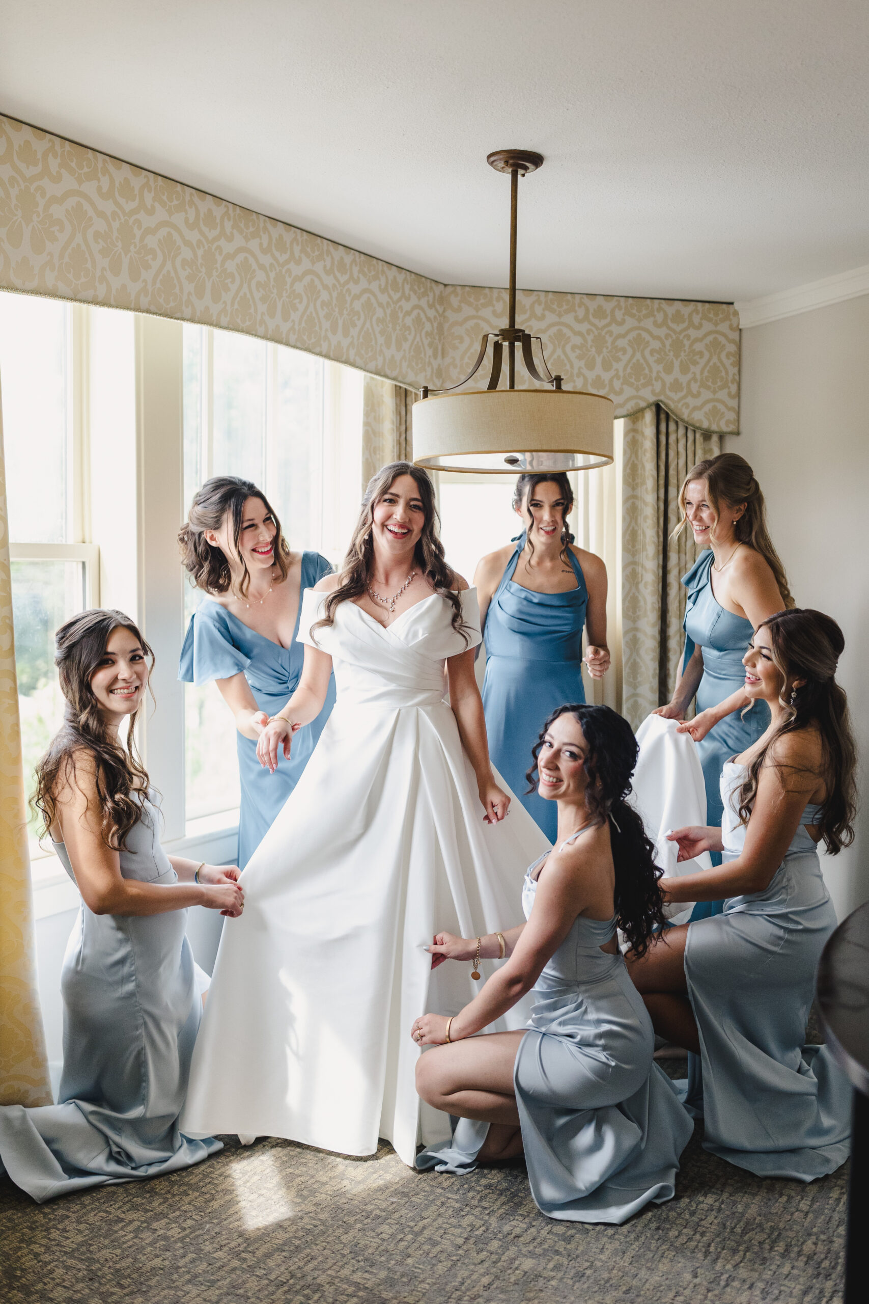a bride laughing with her wedding party inside of a hotel room at the elms hotel in kansas city 