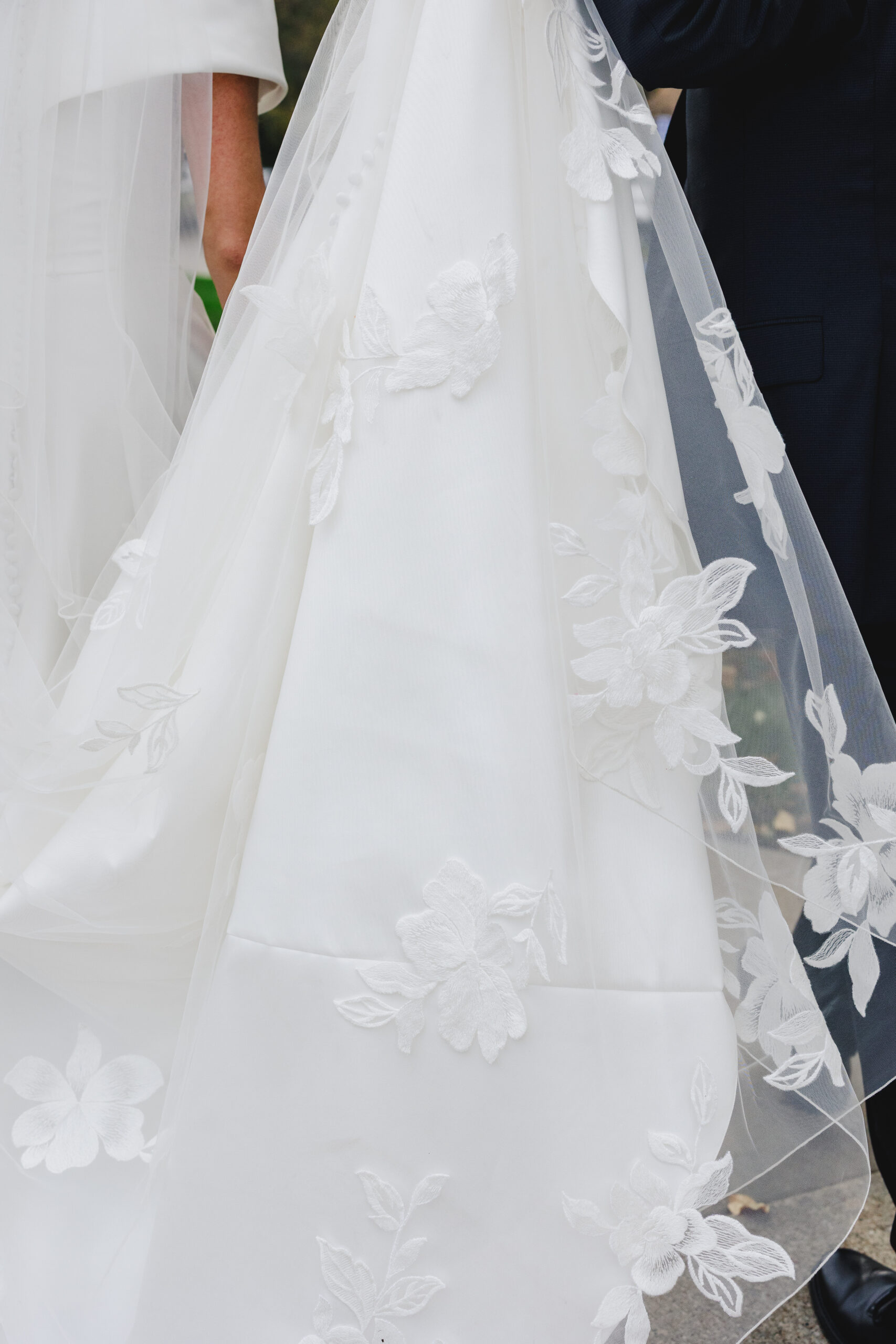 a bride's white wedding dress with flowers stiched onto it 