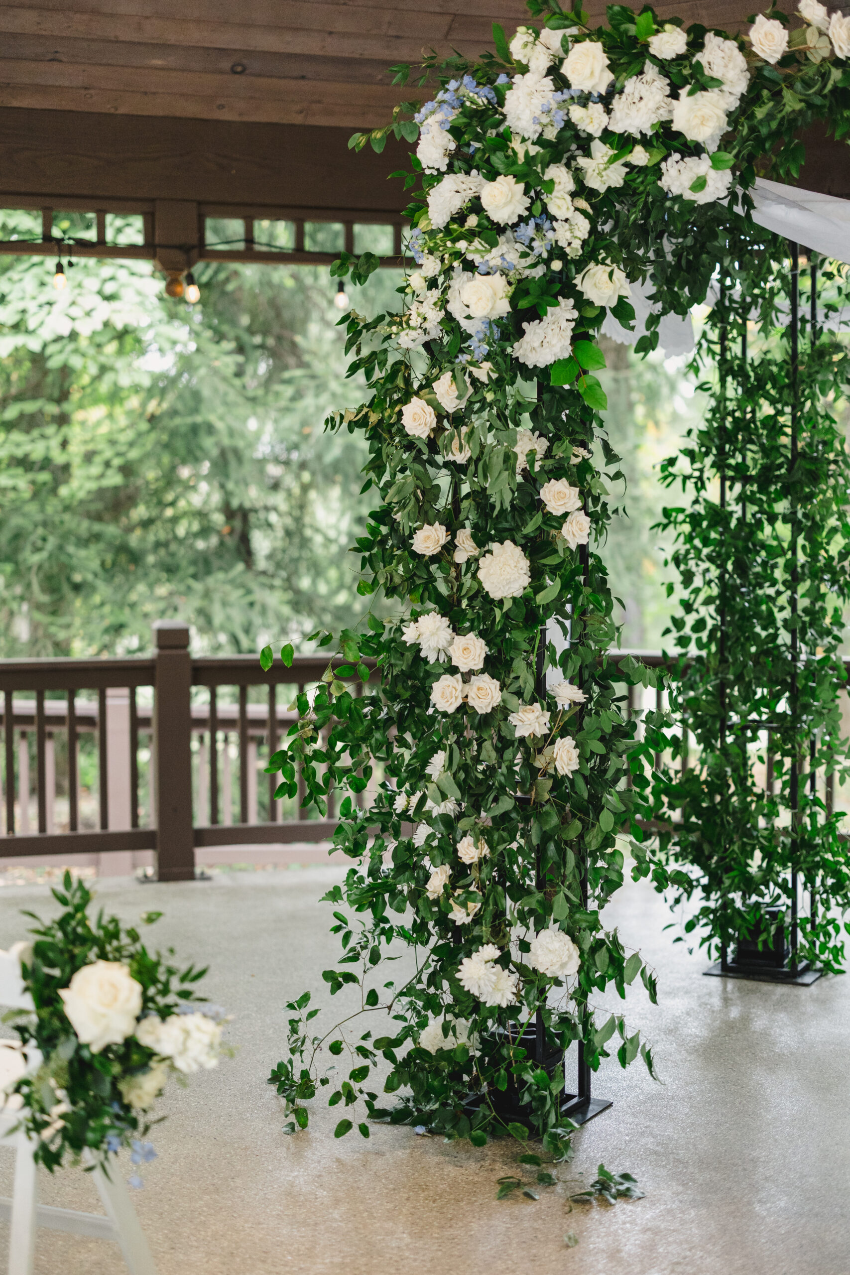 a floral arch with green vines and white flowers inside of a gazebo set up for a wedding ceremony 