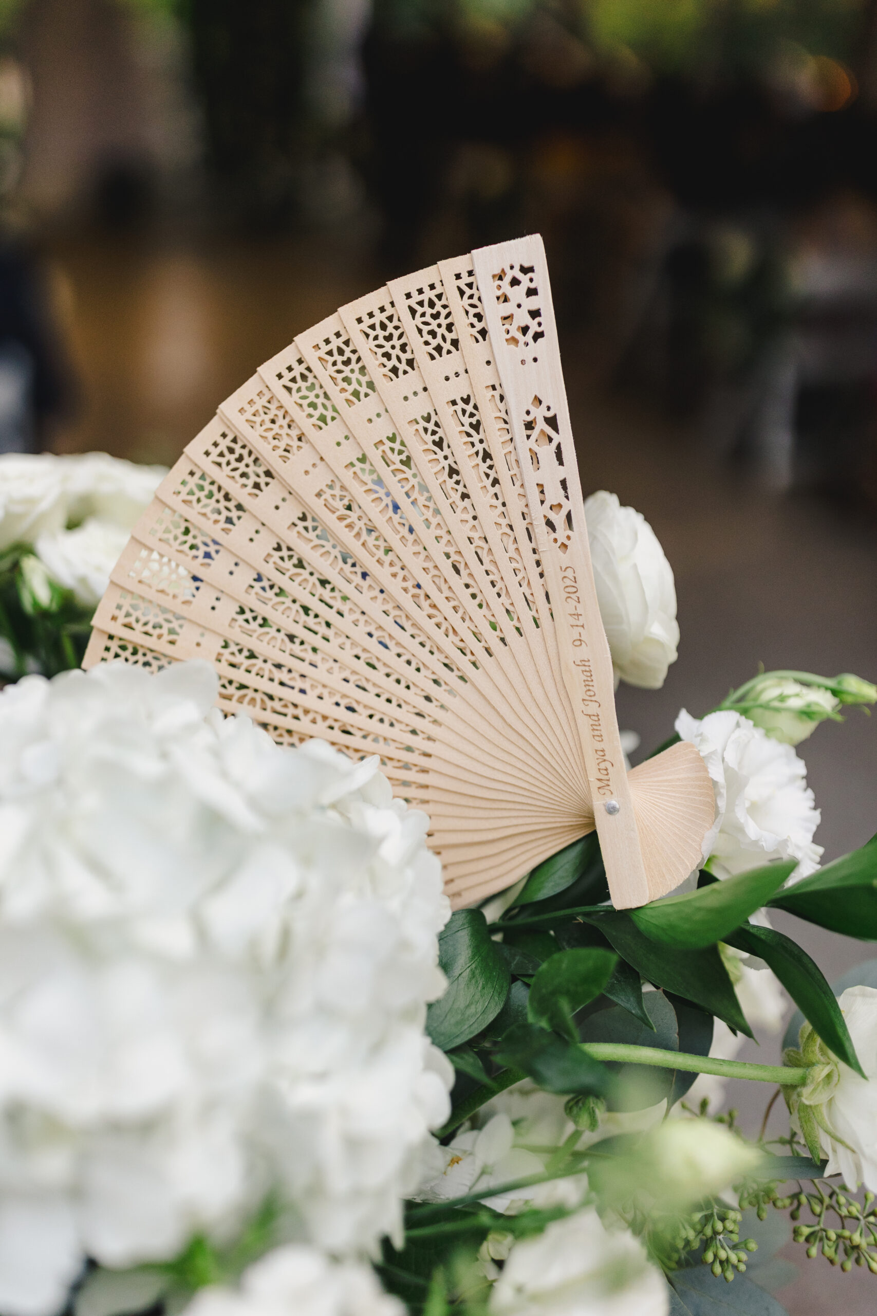 a fan resting on top of a white floral arrangement 