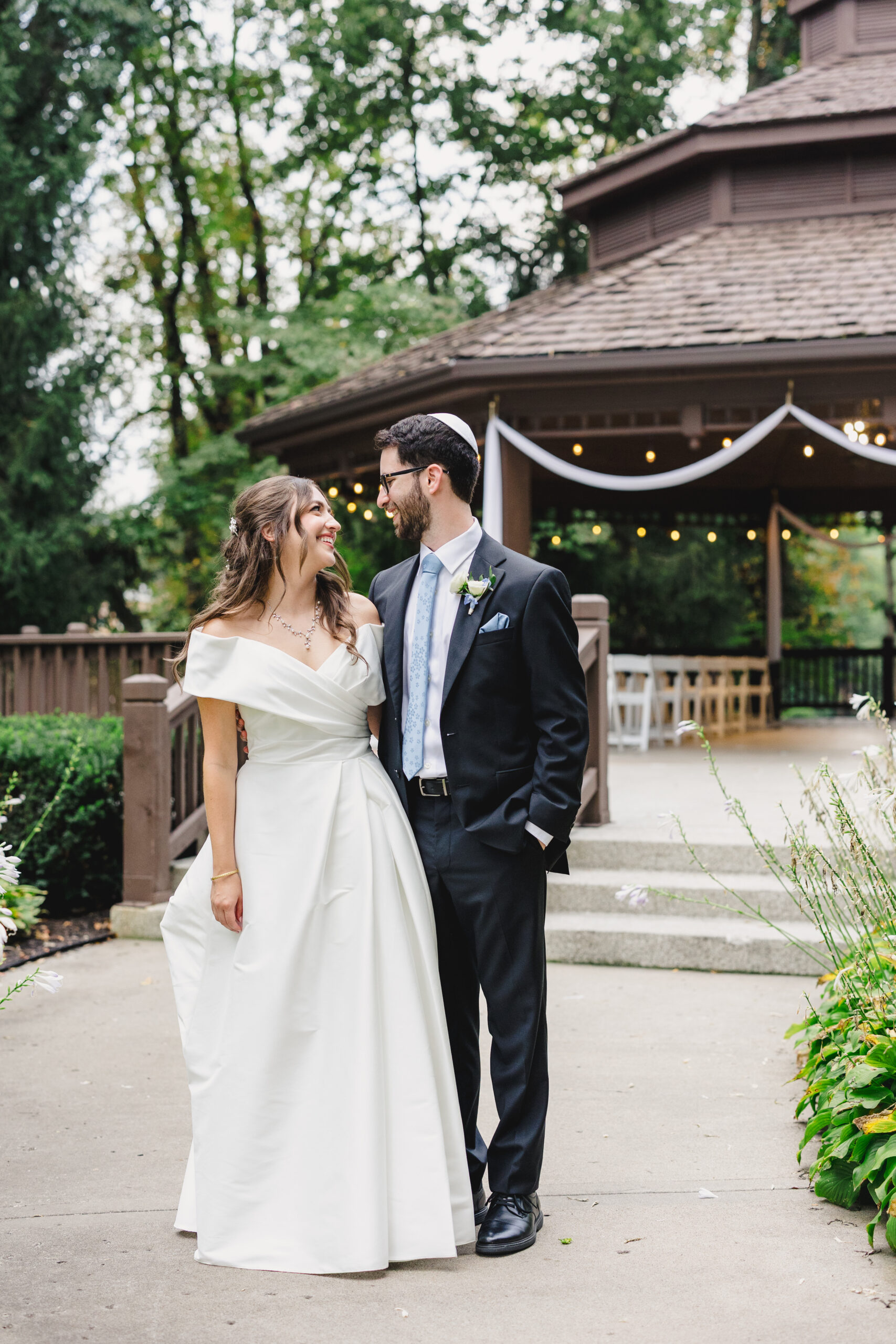 a couple standing in front of the gazebo at the elms in kansas city taking couple wedding portraits before their wedding ceremony