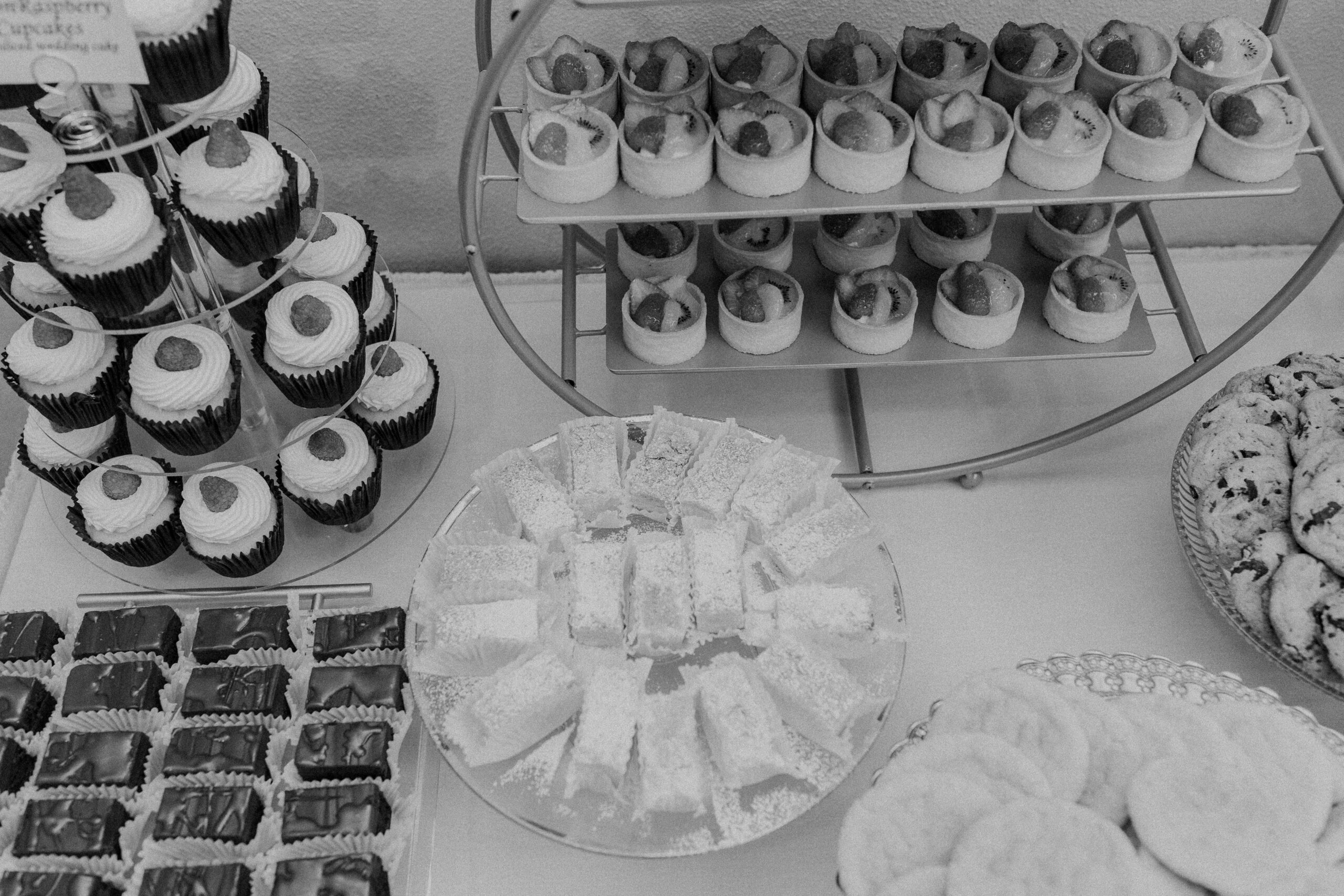 wedding desserts on top of a table at a wedding reception including brownies, cookies, and cupckaes 