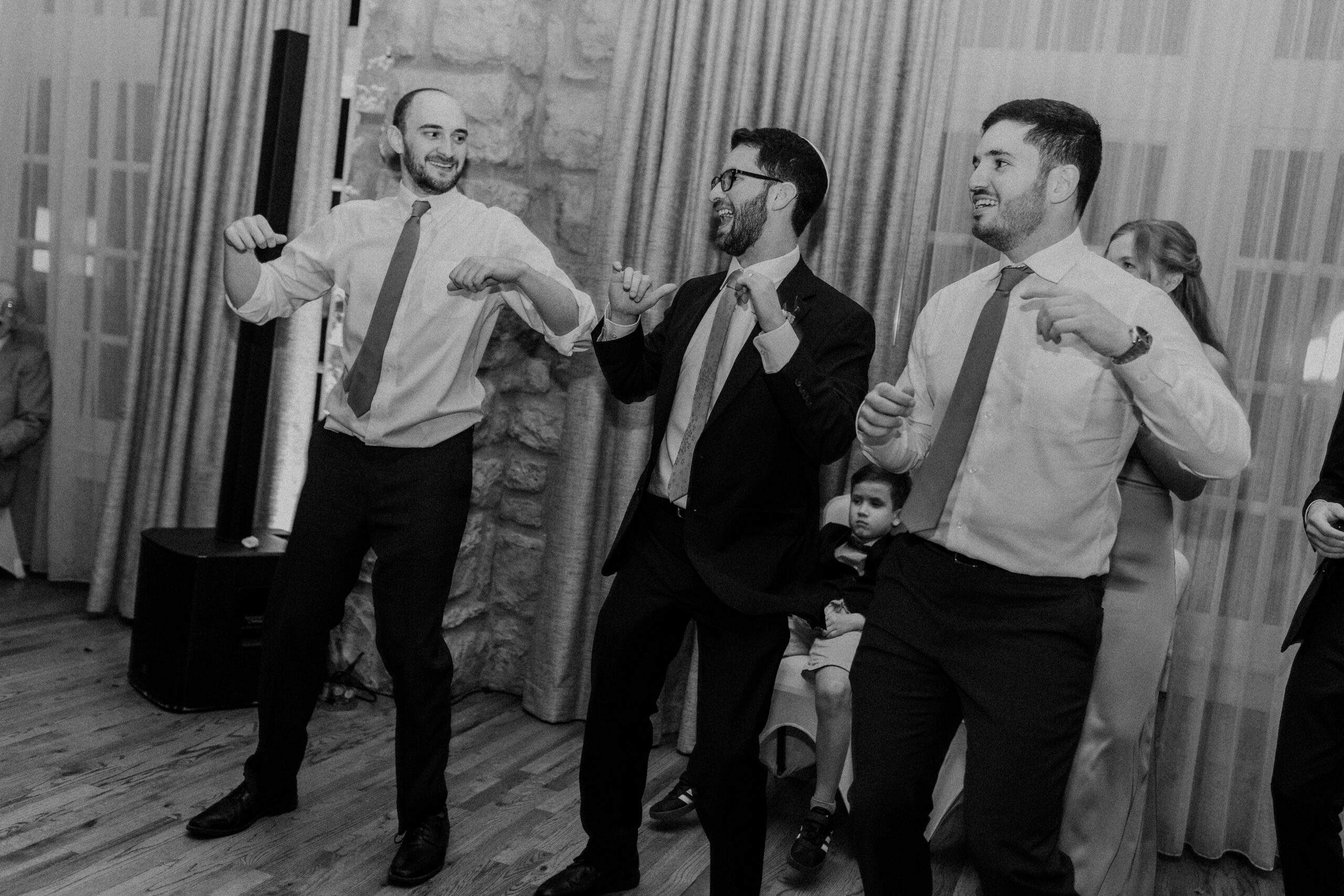 a groom dancing with two of his wedding guests at his wedding reception 