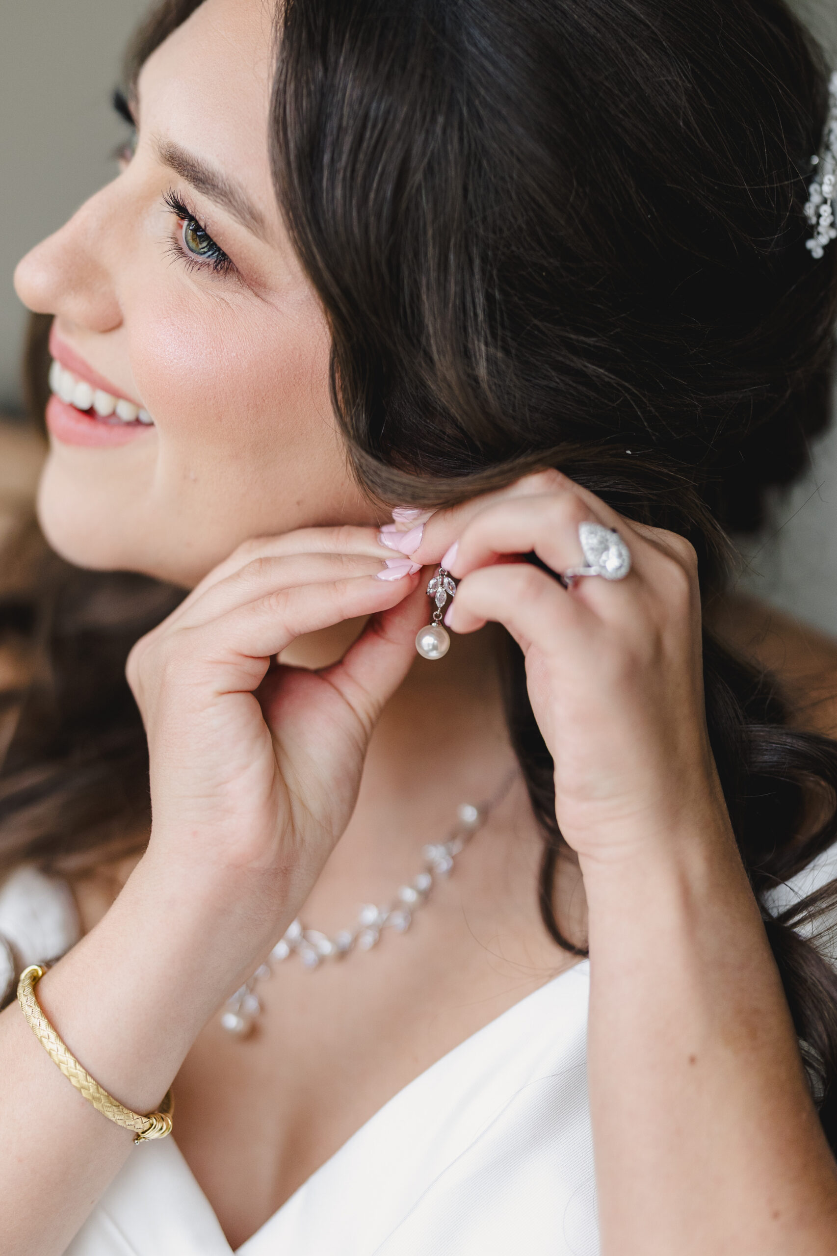 a woman putting on pearl earrings on the day of her wedding 