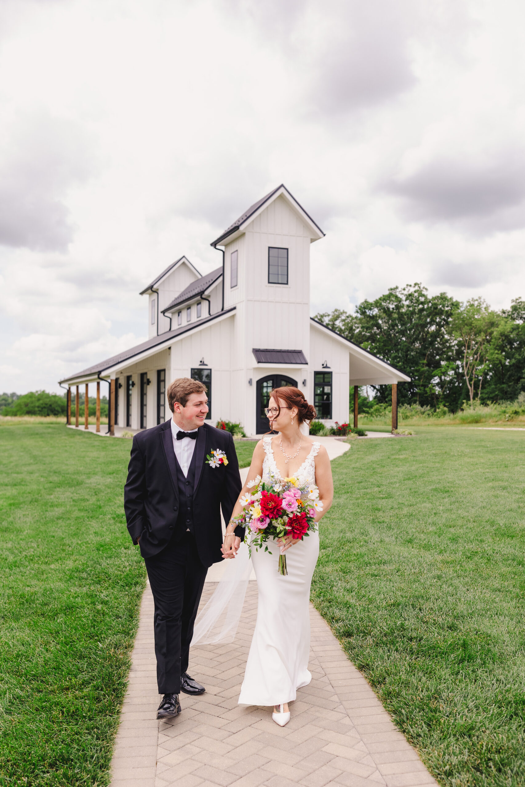 a couple walking hand in hand with each other in front of a white church on the sidewalk 