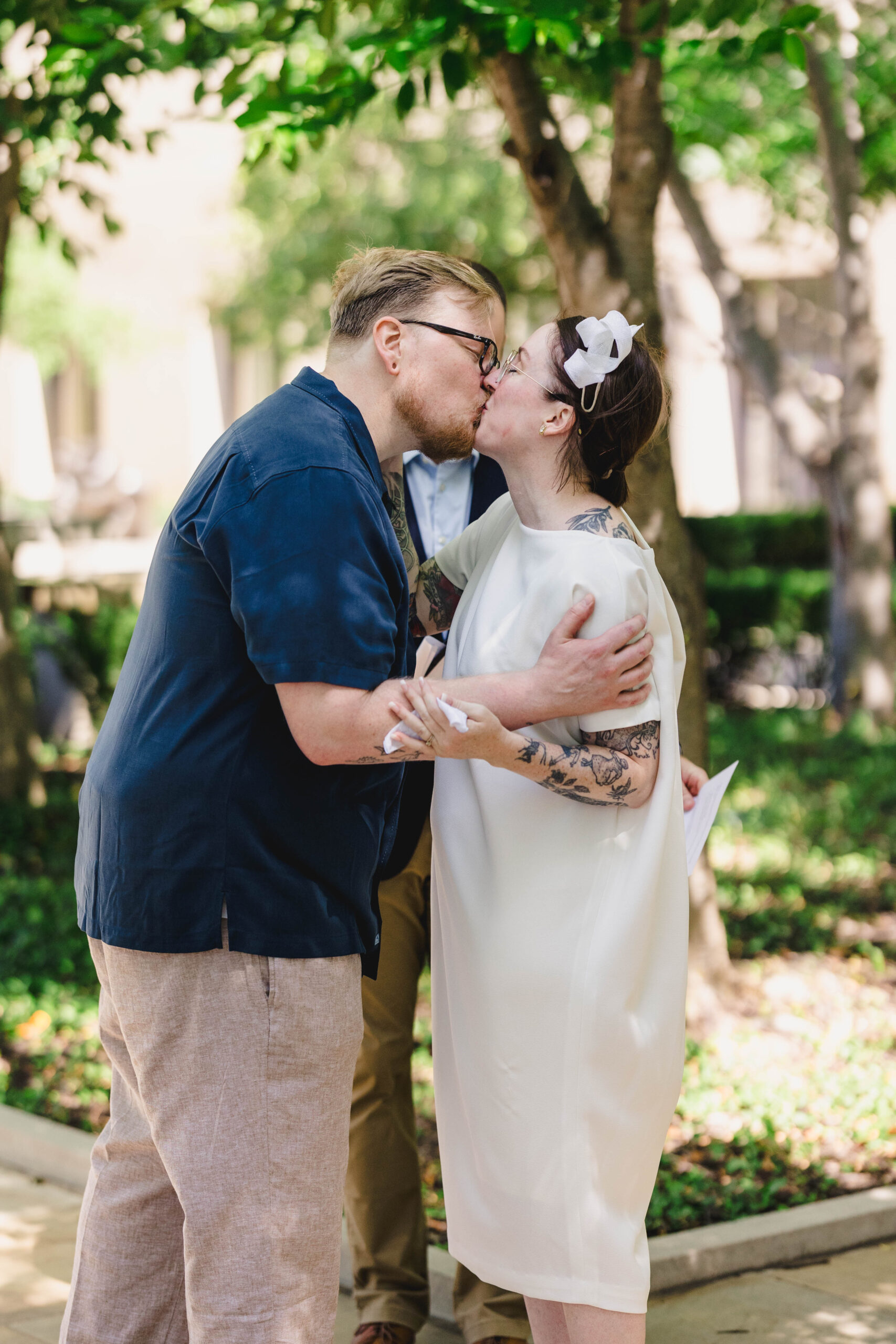 a man and woman kissing in front of their officiant at their wedding ceremony 