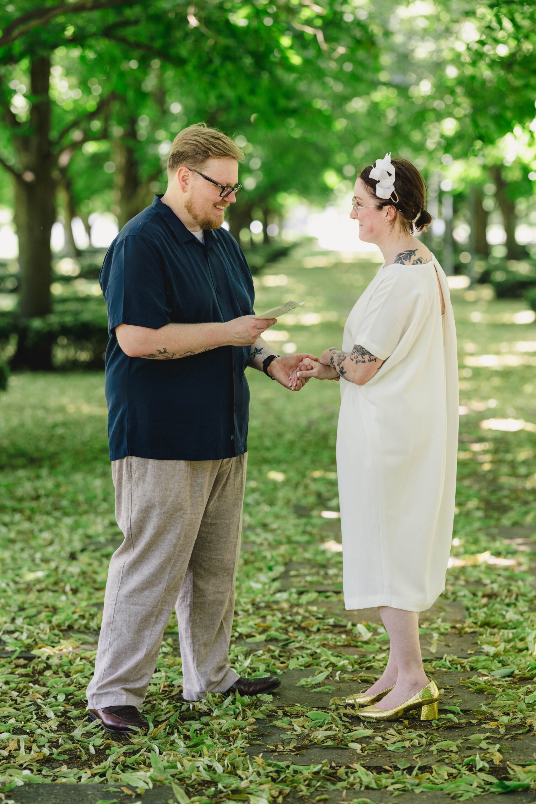 a man and woman reading private vows to each other in the grass after their wedding ceremony 