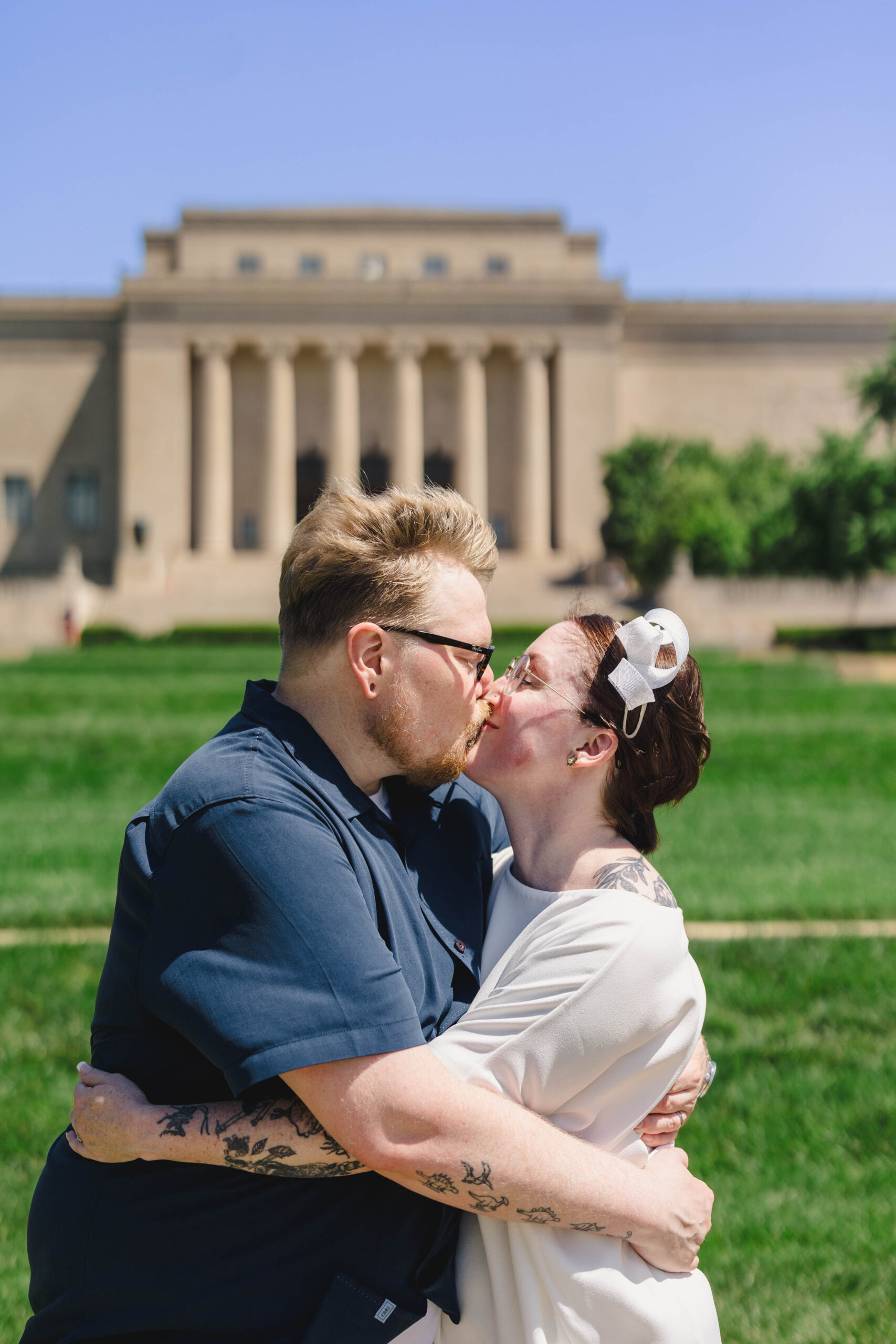 a couple kissing each other and embracing in front of the nelson atkins museum after their wedding ceremony