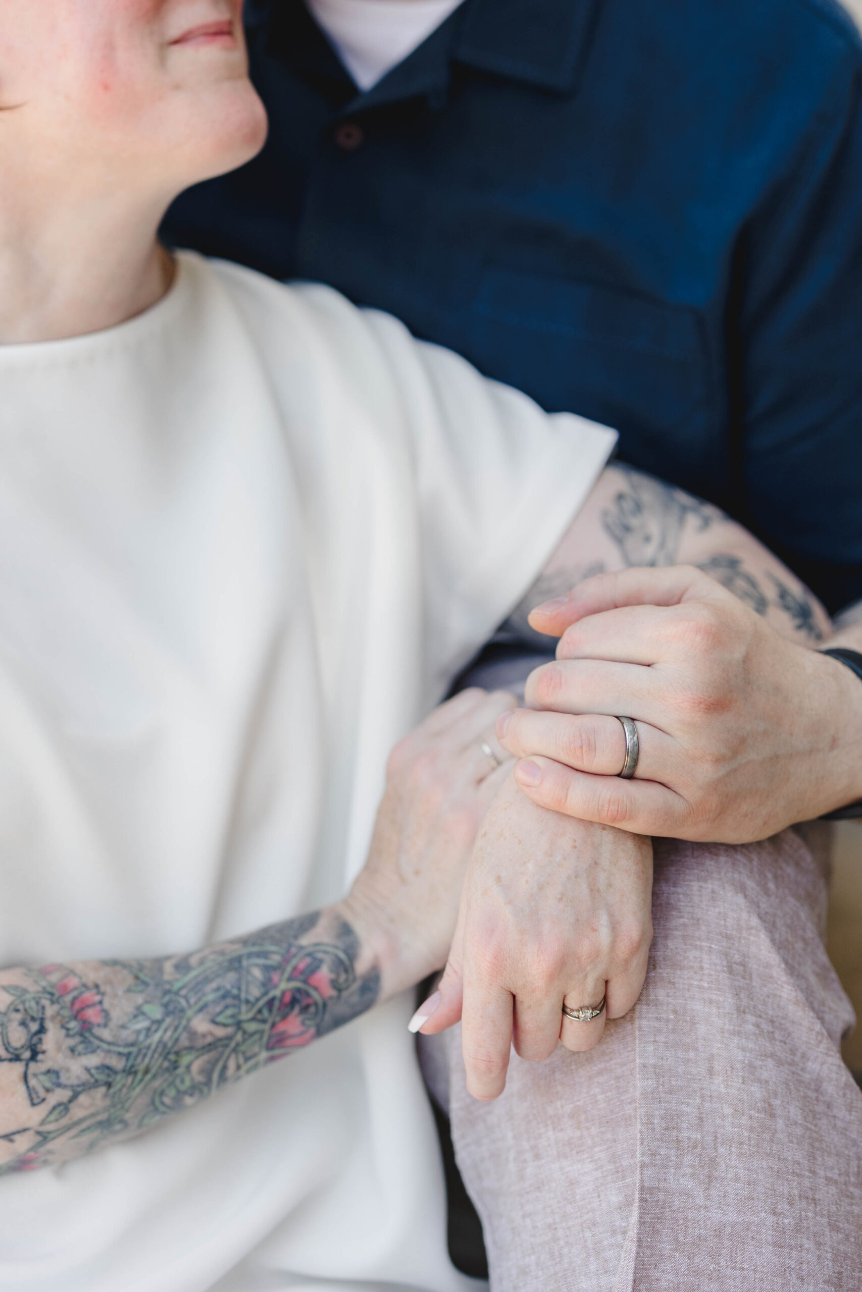 a close up of a man and woman sitting together showing off their wedding rings and looking at each other 