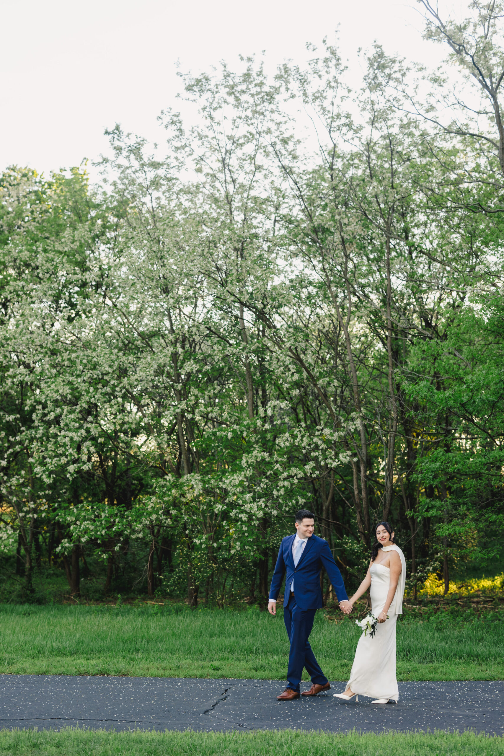a bride and groom walking down a sidewalk holding hands at sunset after their wedding ceremony