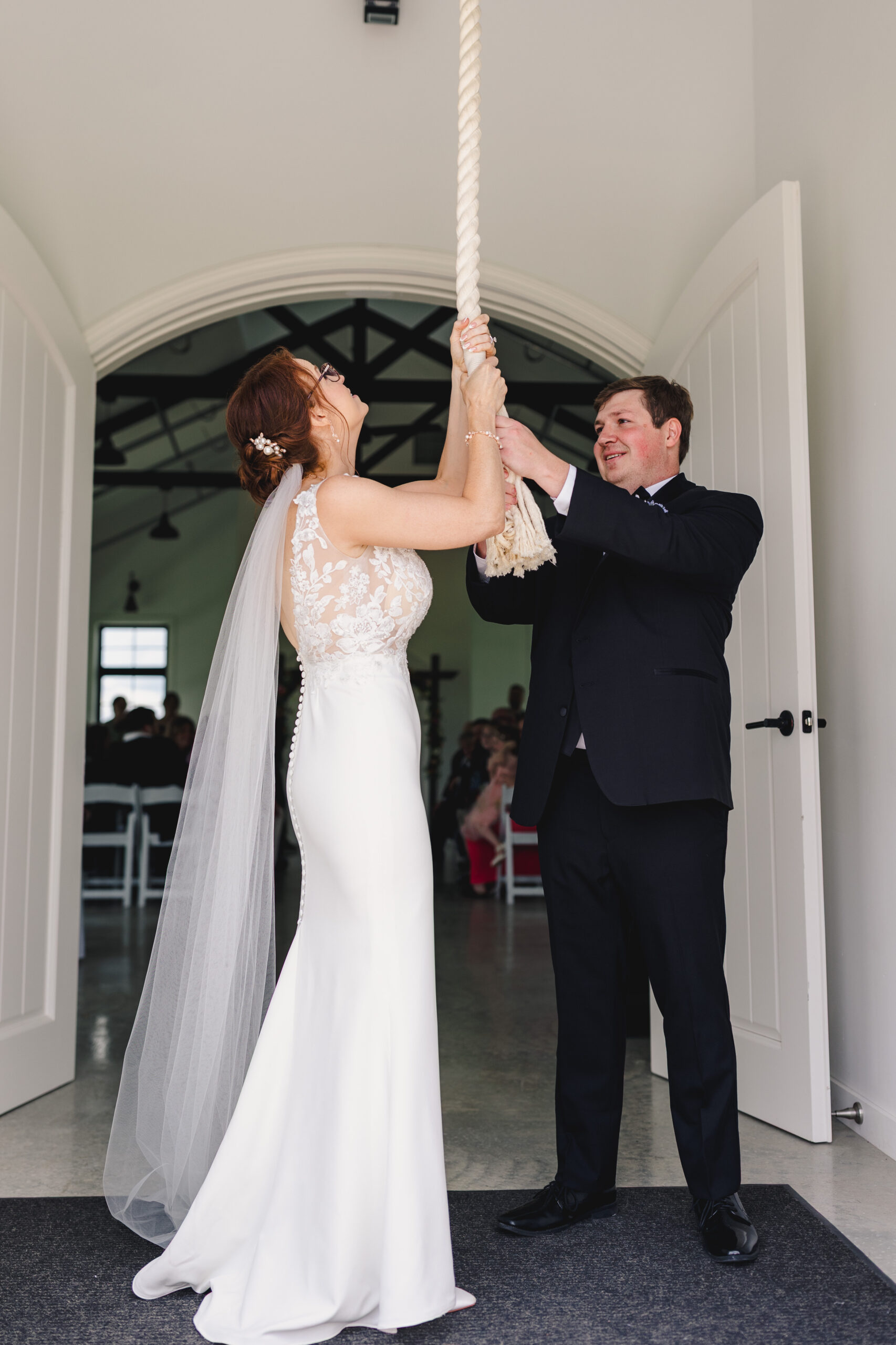 a couple ringing a church wedding bell on the day of their wedding ceremony 
