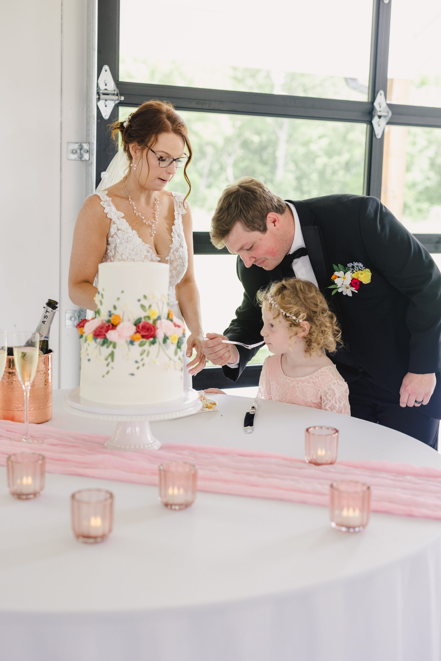 a couple feeding their daughter wedding cake to eat at their wedding reception 