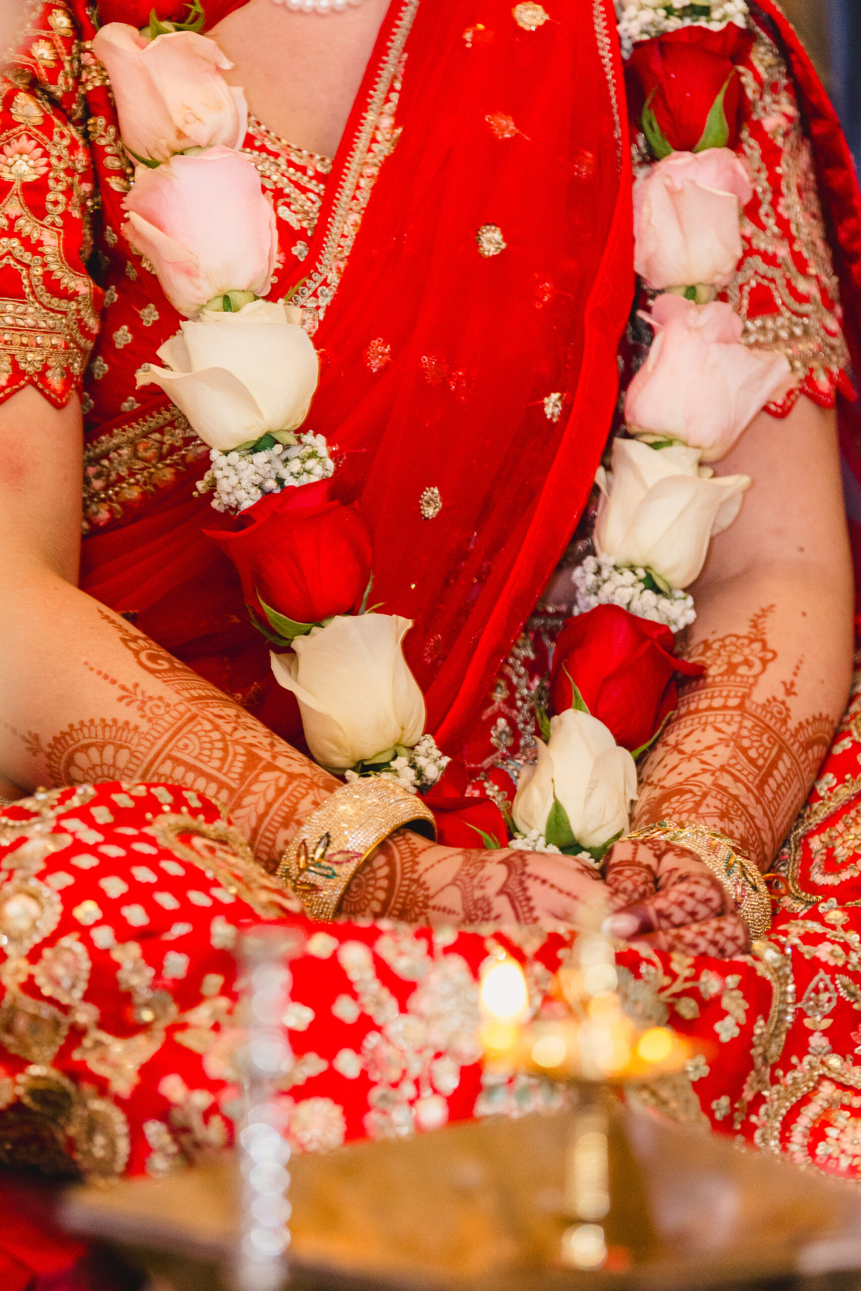 a woman wearing a garland of roses  sitting with her legs crossed and her hands in front of her 