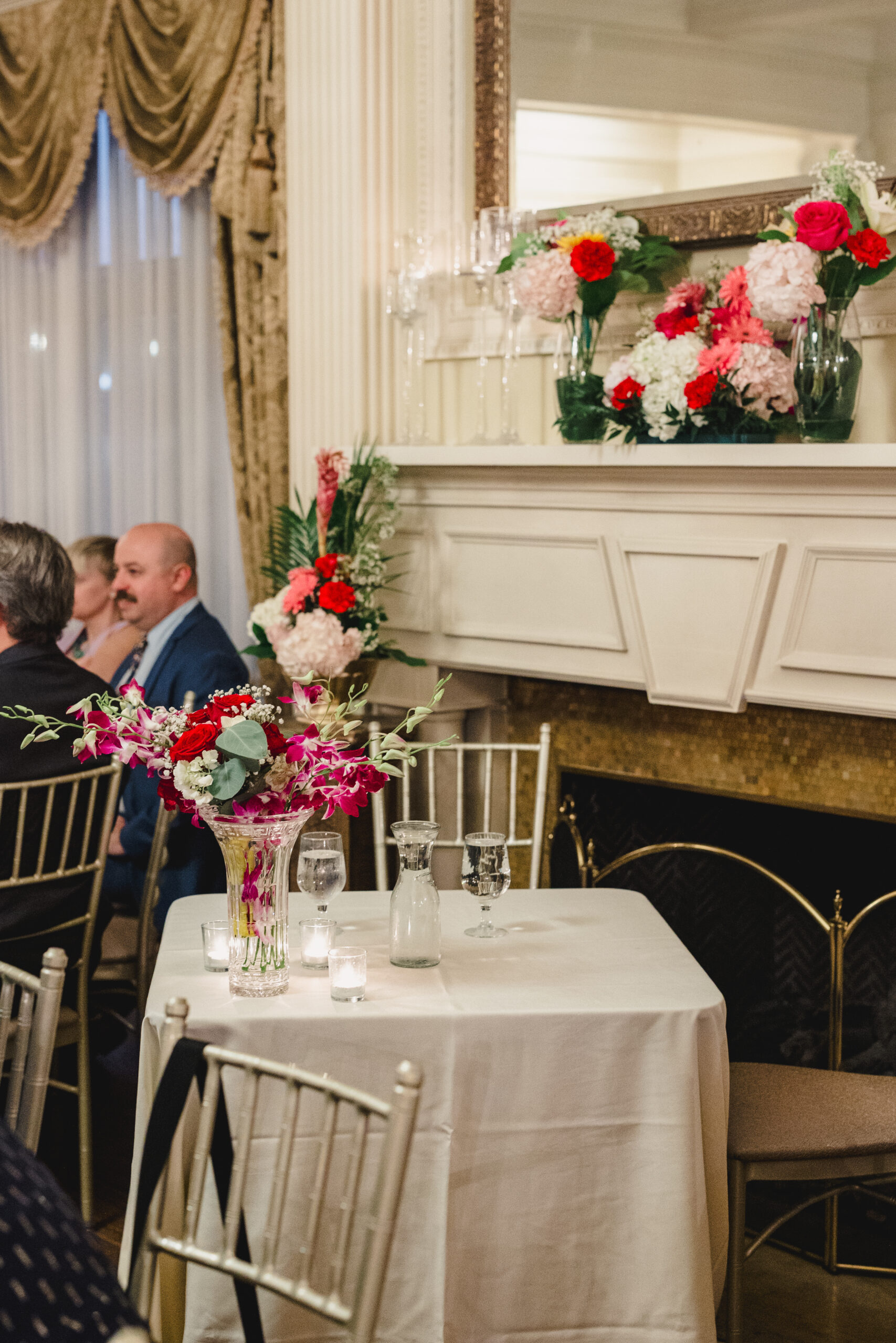 tables set up for a wedding reception inside of loose mansion with colorful flowers in vases on top of them 