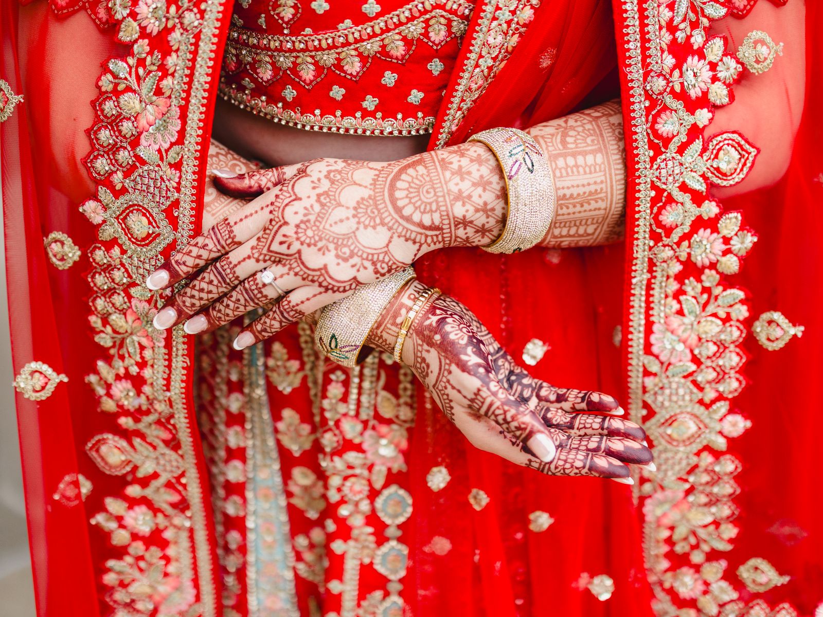 a woman wearing traditional indian wedding attire and showing off her hands that are painted with henna 