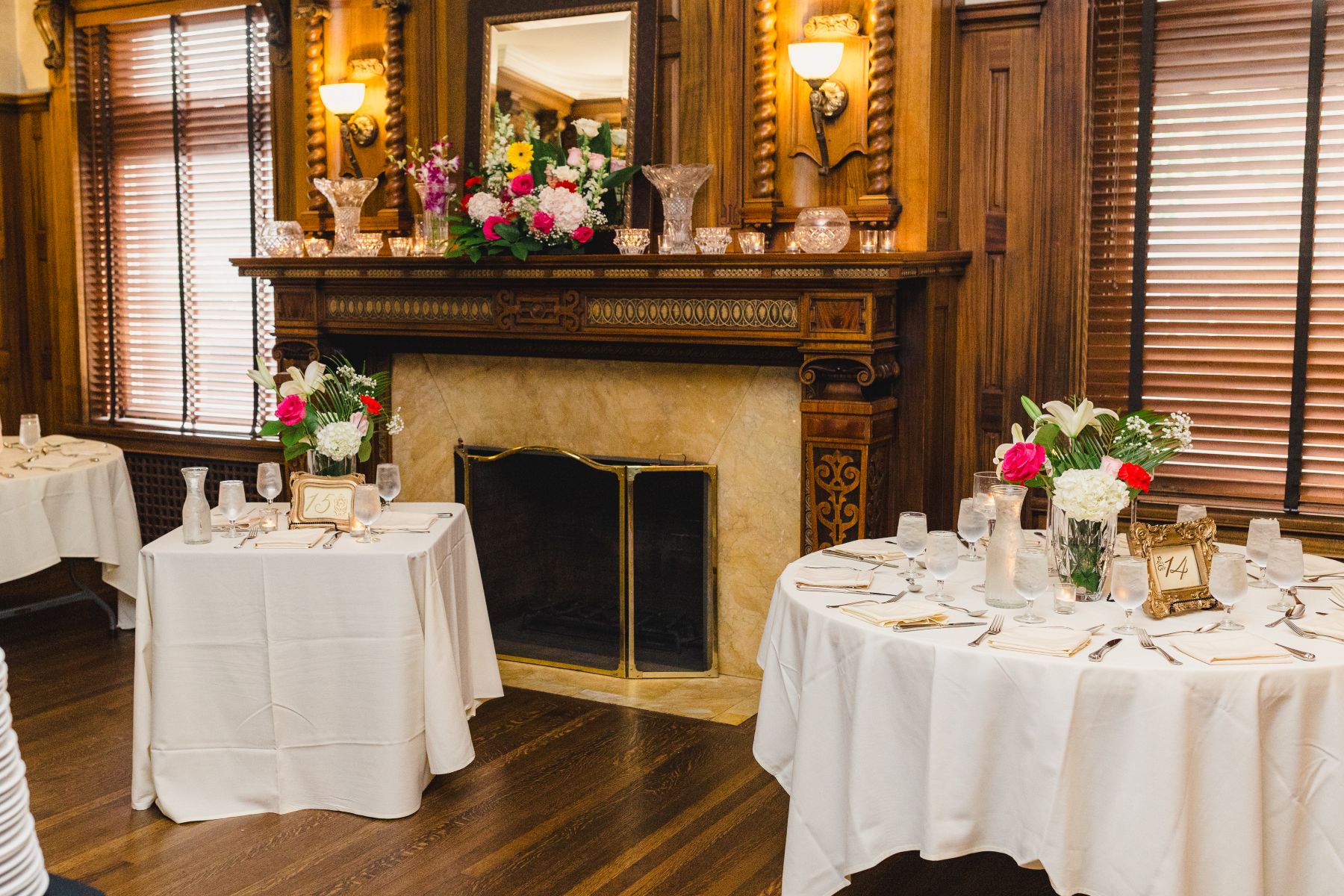tablets set up with cutlery, flowers, and glasses for a wedding reception inside of loose mansion 