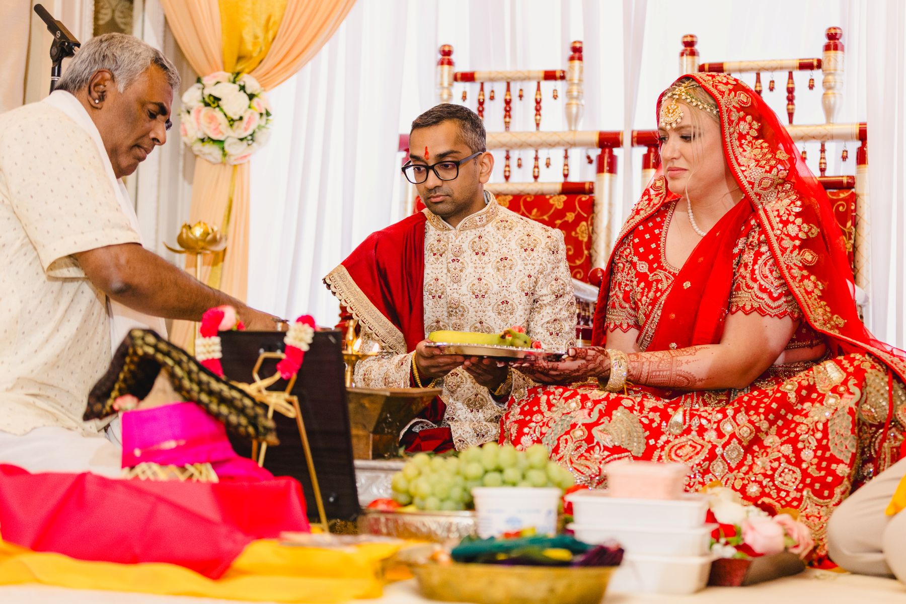 a couple sitting on the ground having a traditional indian wedding ceremony