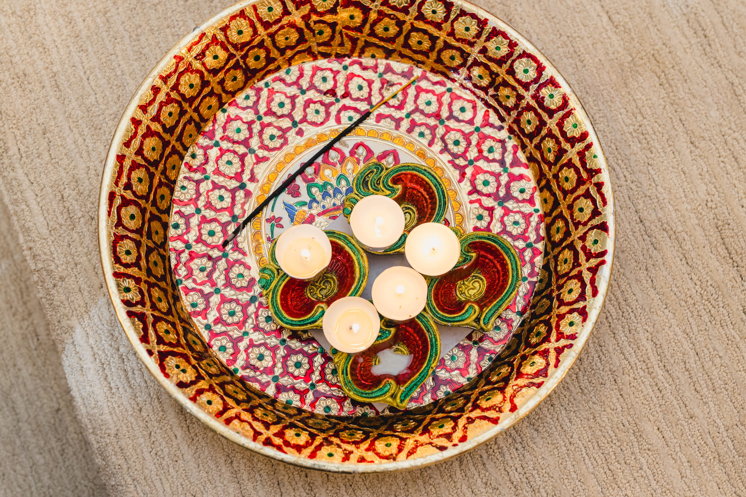 a bowl on the ground with candles inside of it 