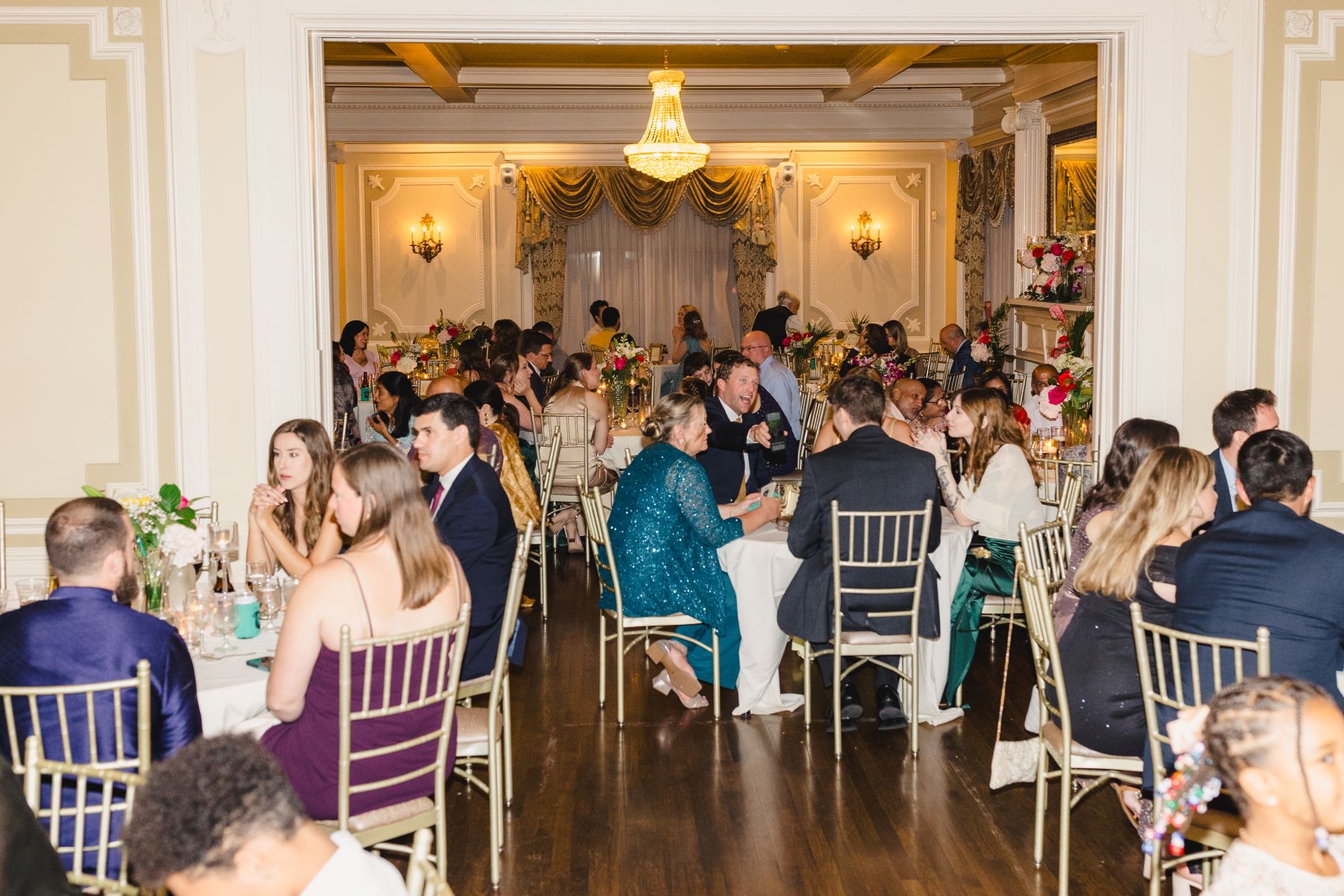 guests seated for dinner at a wedding reception inside of loose mansion 