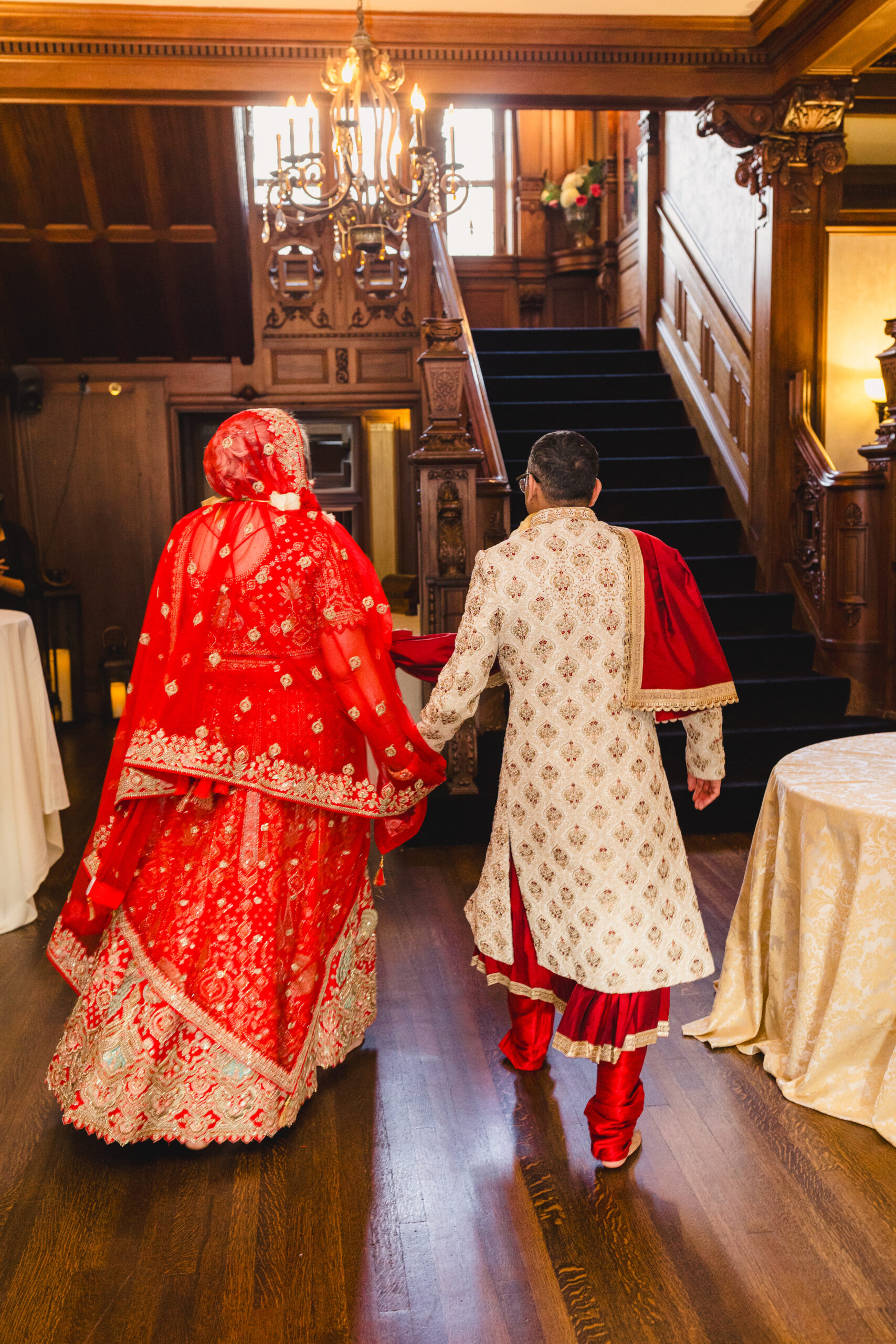 a copule walking hand in hand thorugh loose mansion after their wedding ceremony 