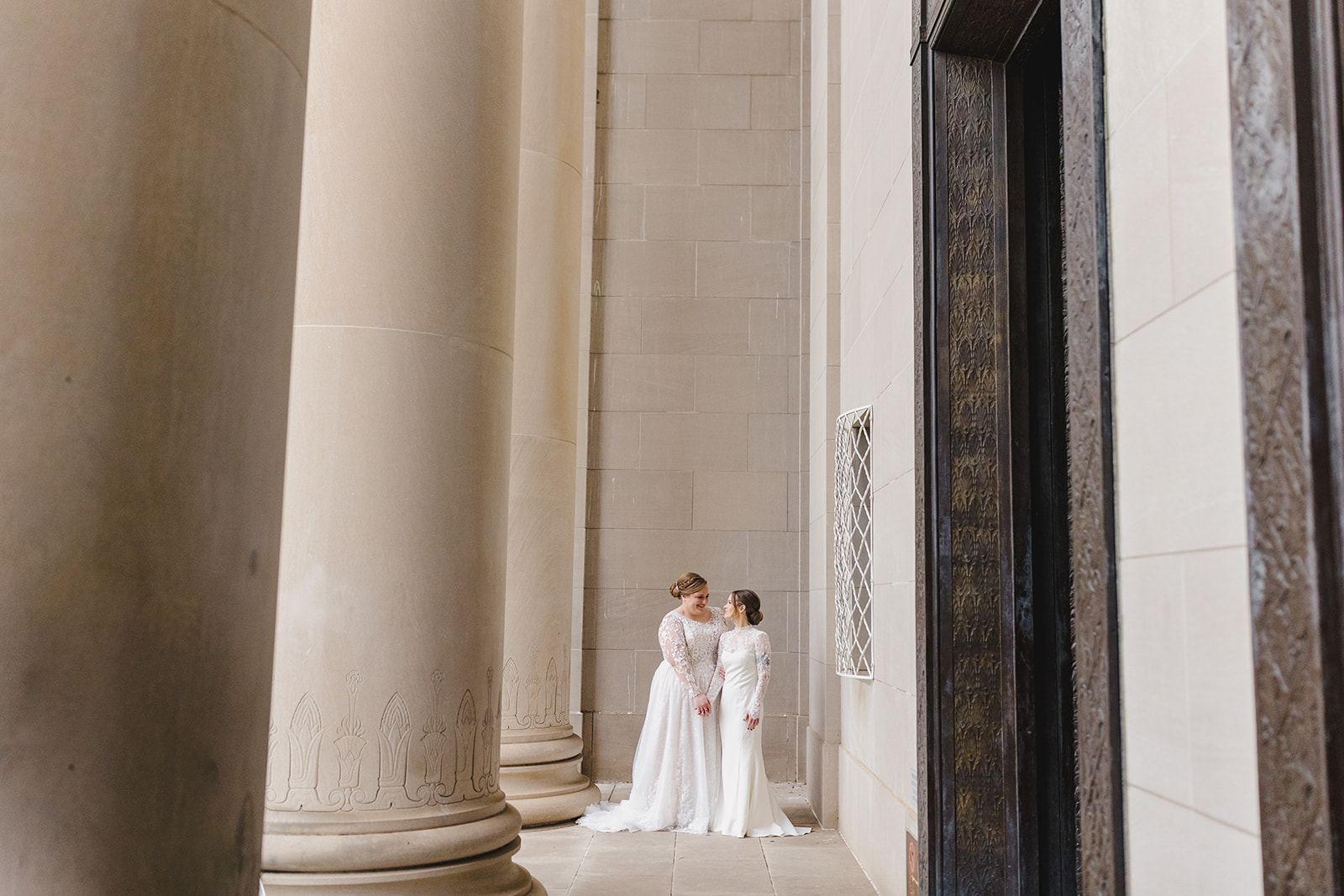 two brides taking bridal wedding portraits in front of the nelson atkins museum in kansas city 