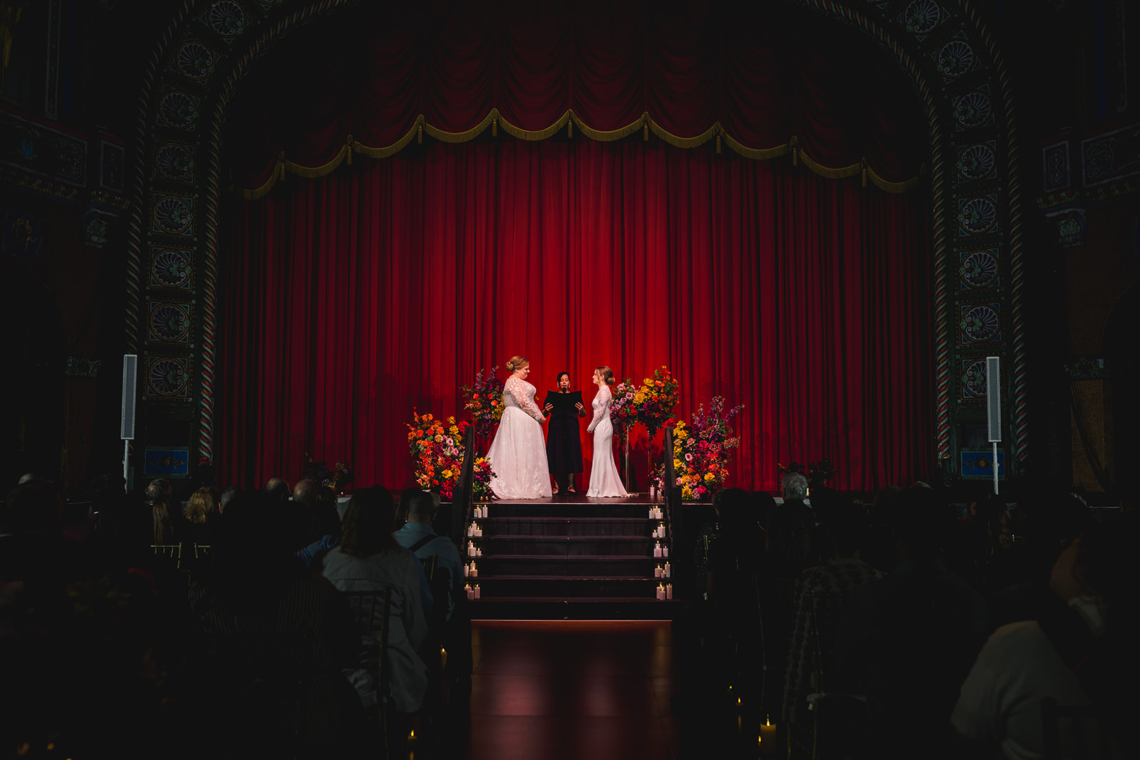 two brides having their wedding ceremony inside the uptown theater in kansas city 