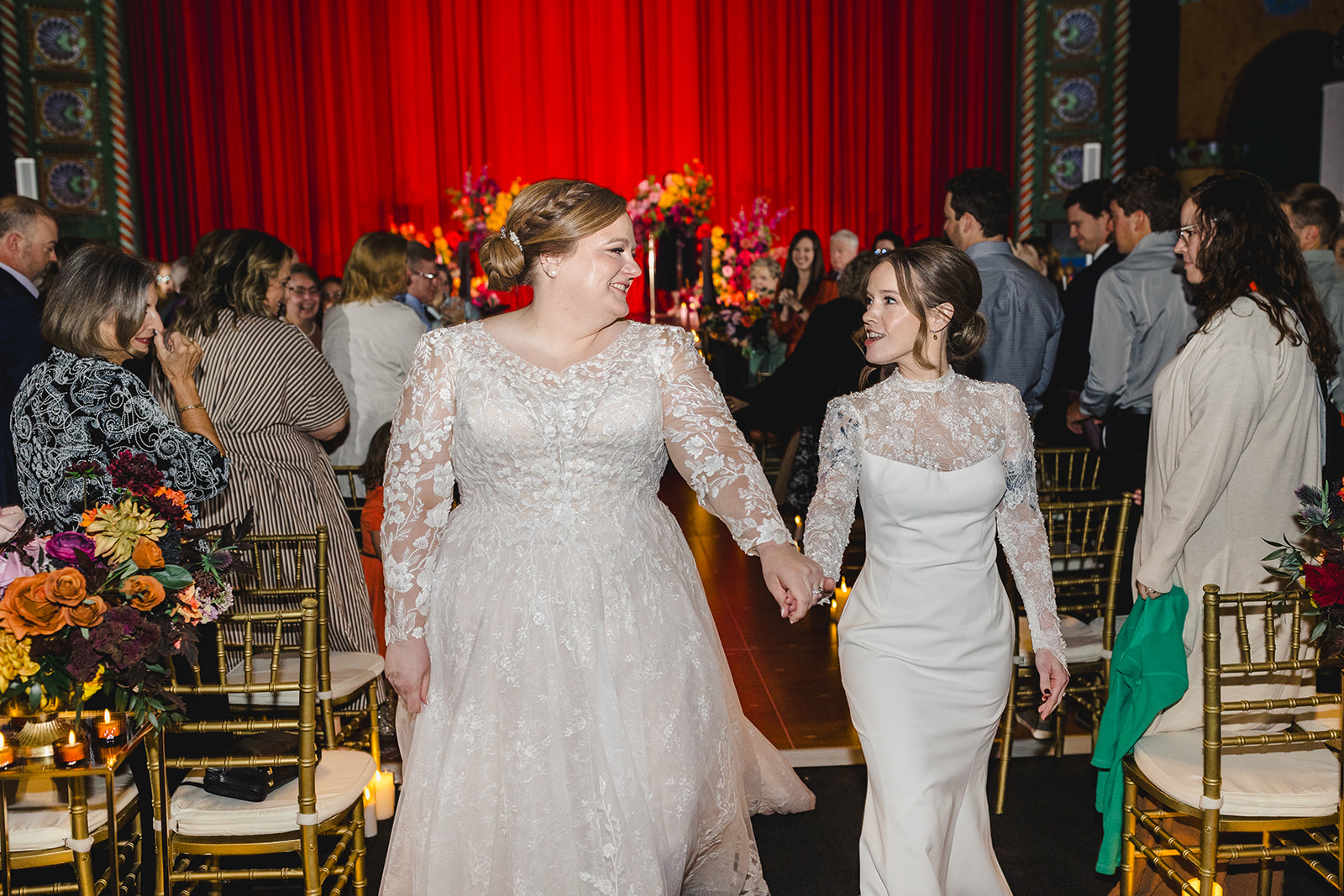 two brides walking down the aisle after their wedding in the uptown theater in kansa city 
